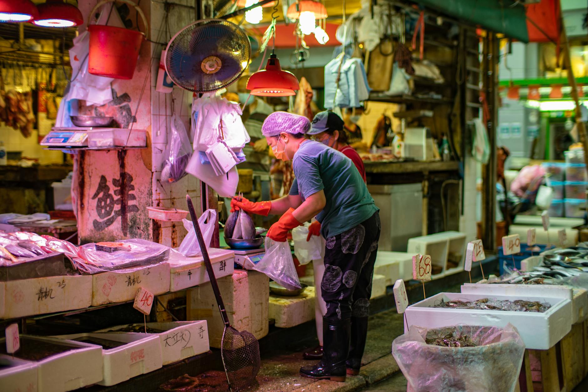 Vibrant scene of a fish vendor weighing seafood at a Hong Kong market.