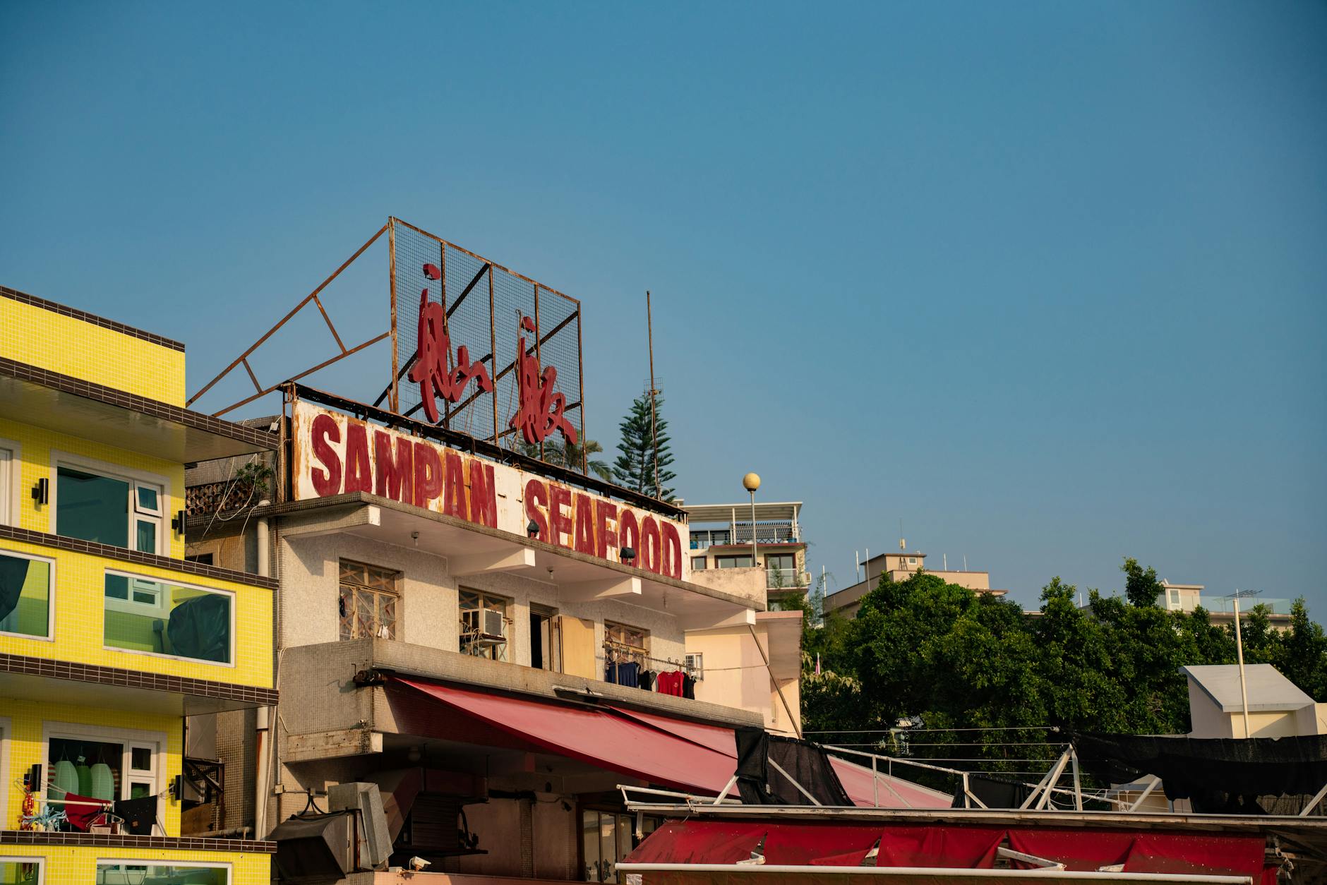 Sampan Seafood restaurant signage on building facade in Hong Kong under clear blue sky.