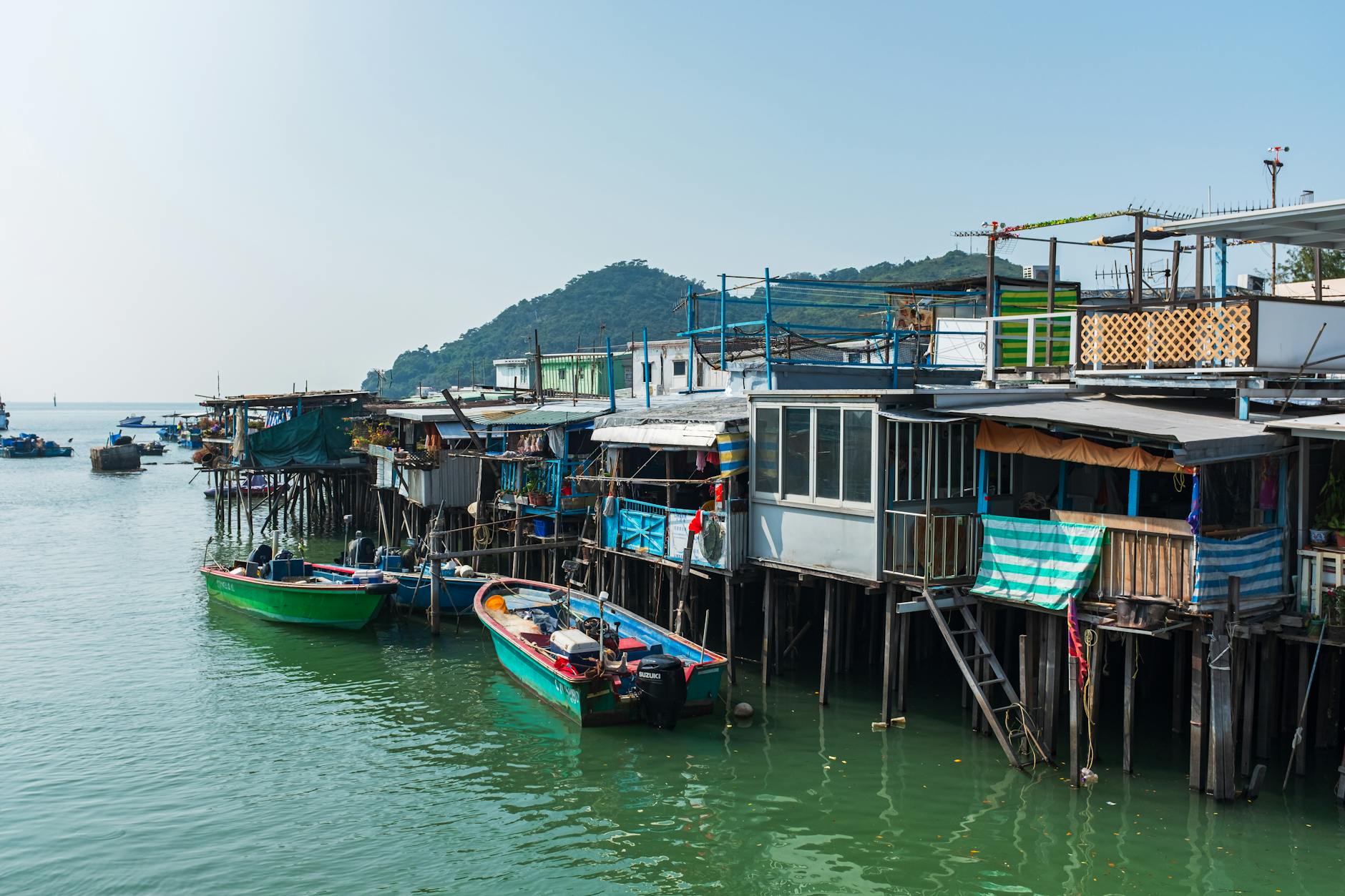 Scenic view of stilt houses along waterfront in New Territories, Hong Kong, with moored colorful boats.