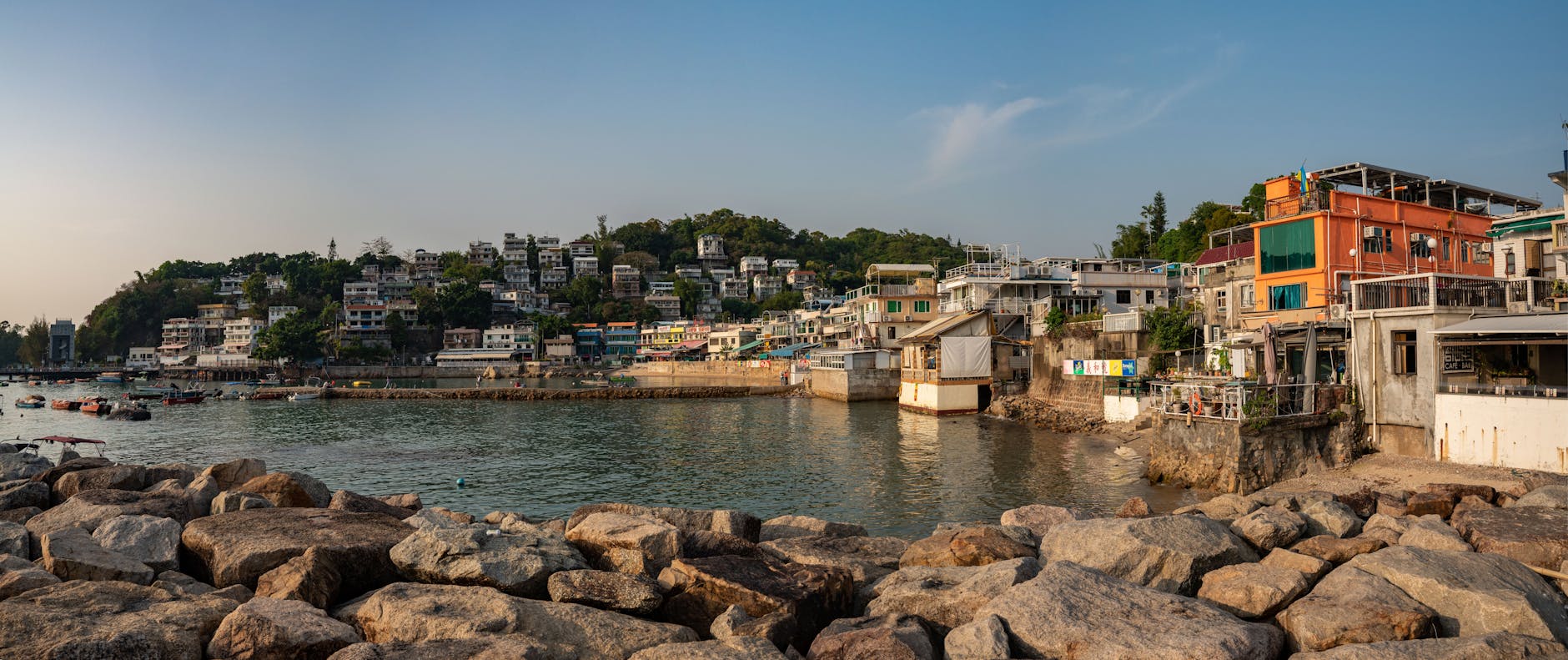 Panoramic view of a scenic Hong Kong fishing village, showcasing colorful buildings by the sea.