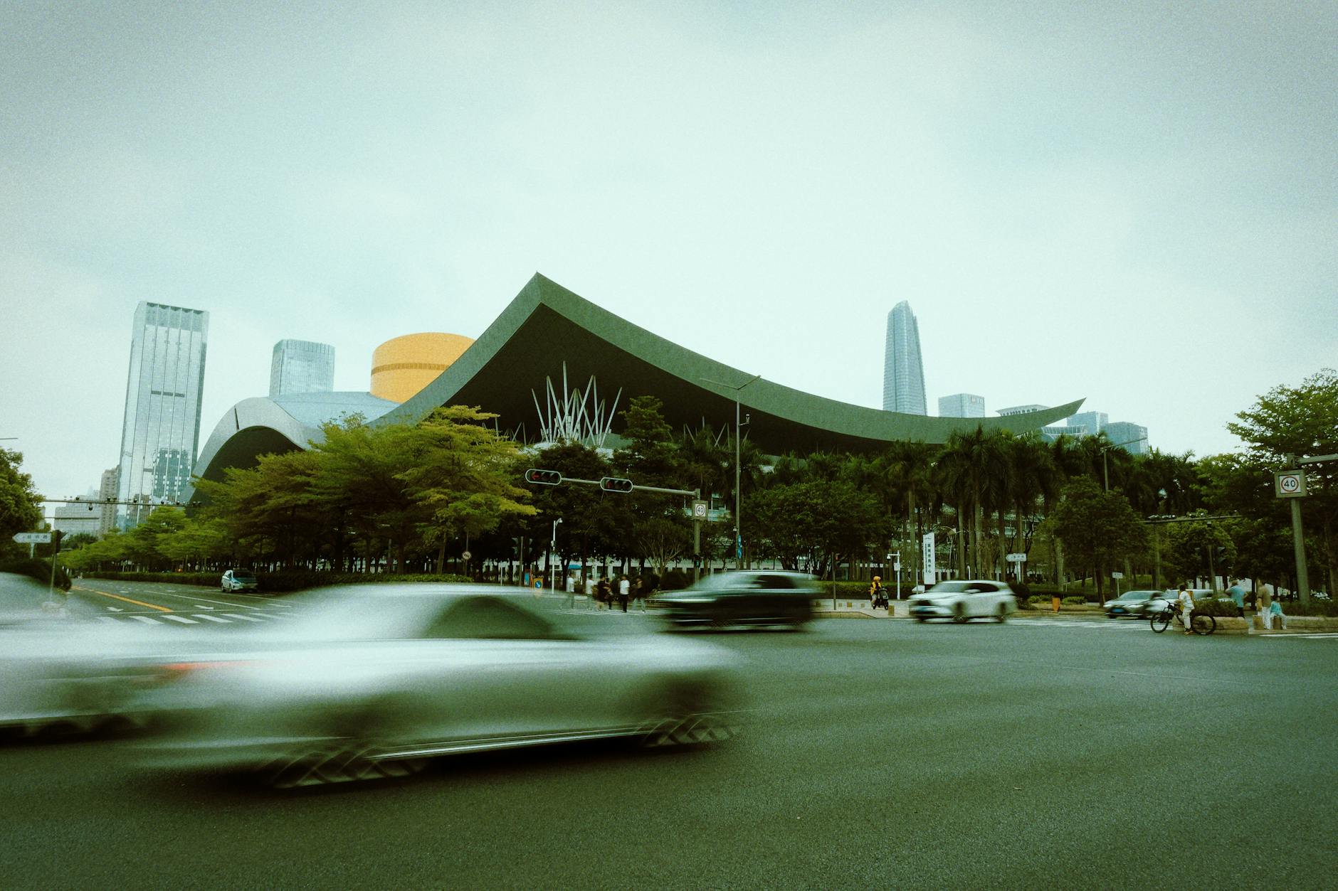 Blurred motion of traffic in front of Shenzhen Civic Center in China, showcasing vibrant city life.
