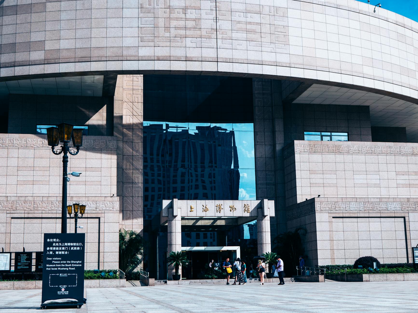 The grand entrance of Shanghai Museum showcasing modern architecture under a clear blue sky.