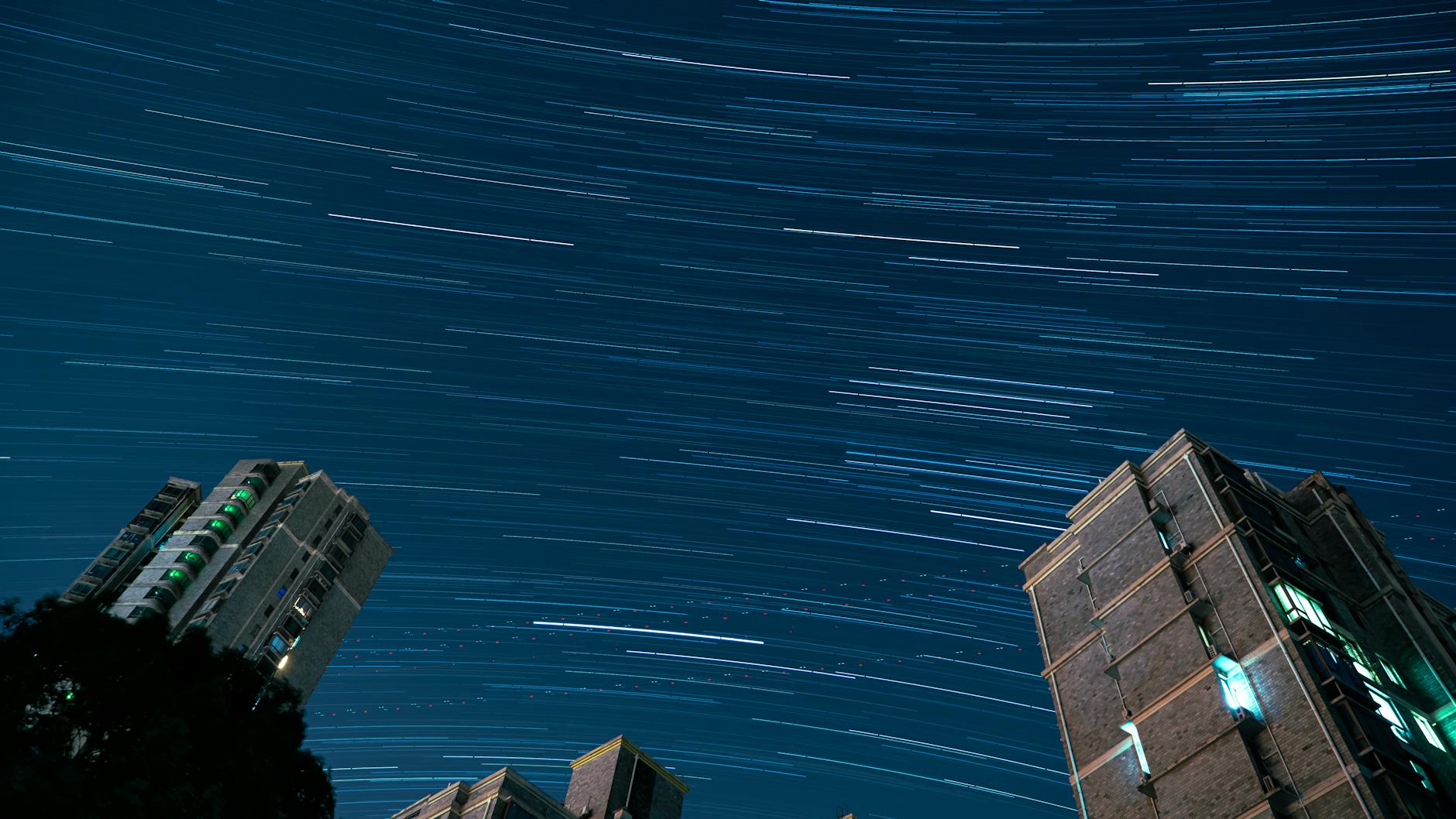 A stunning long exposure of star trails over urban apartment buildings in Shanghai at night.