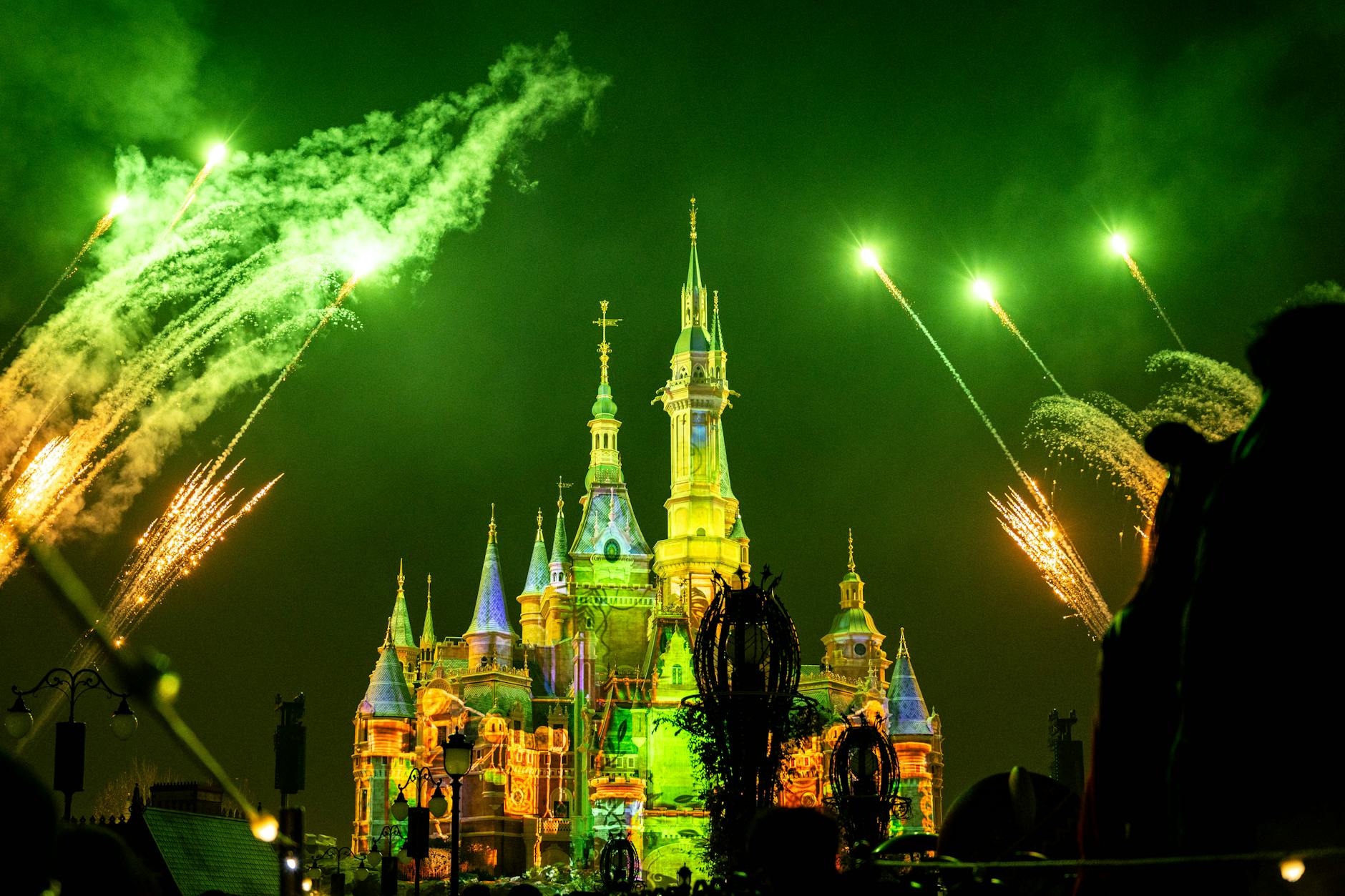 Spectacular night fireworks lighting up an enchanted castle with vibrant green hues in Shanghai, China.
