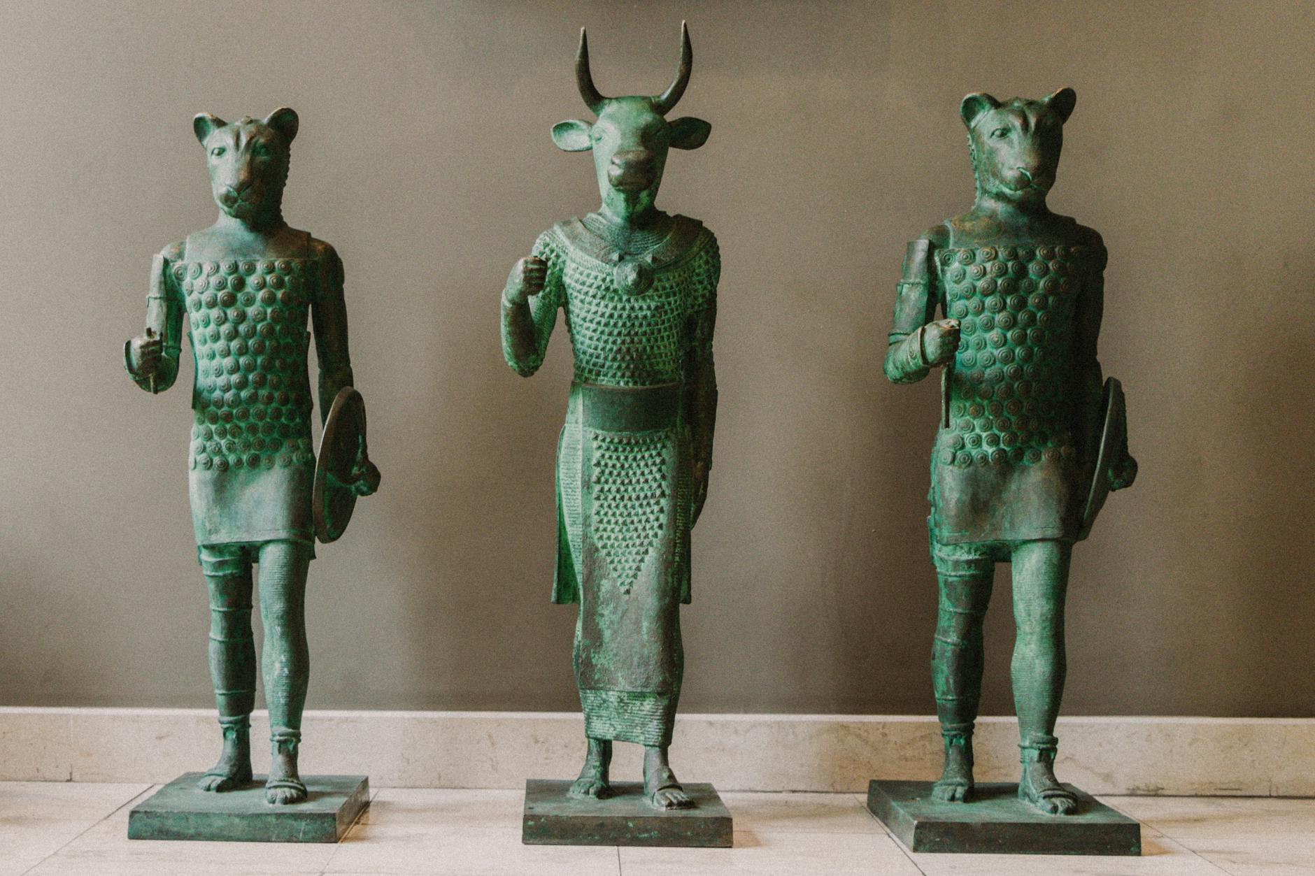 Bronze statues depicting ancient horned and animal figures in a museum setting.