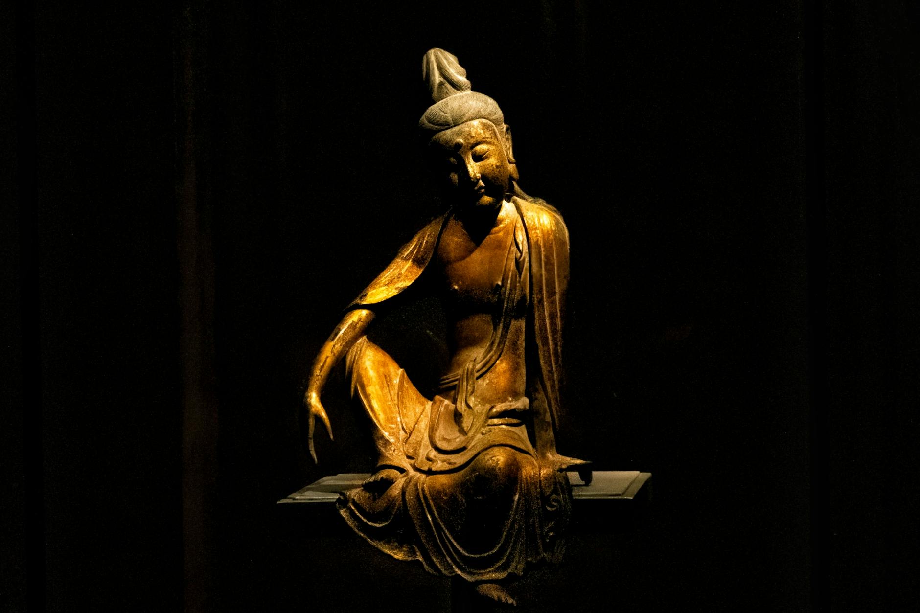 Bronze Buddha statue captured in low light, showcasing serene posture.