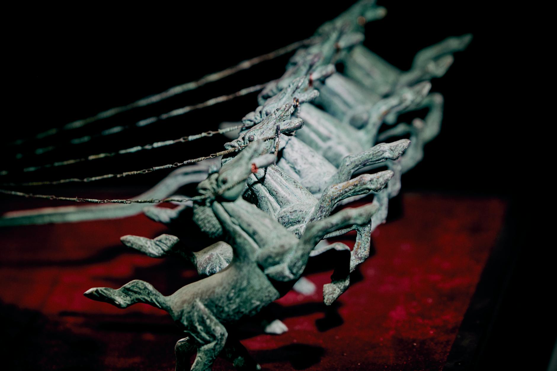 Detailed close-up of antique horse figurines with subtle lighting and dramatic shadows.