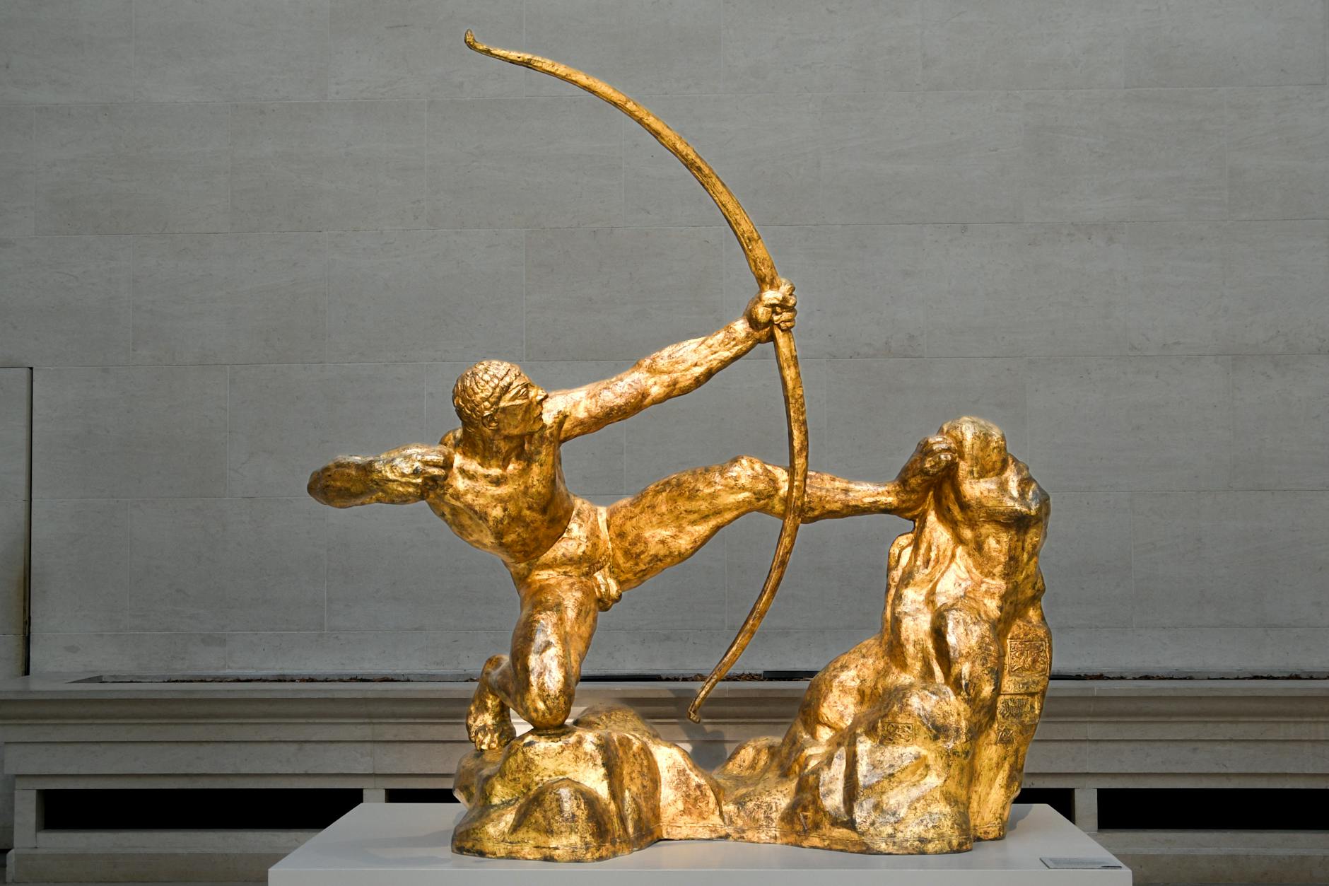 Golden archer sculpture in museum exhibit captures ancient Greek mythology in timeless art.