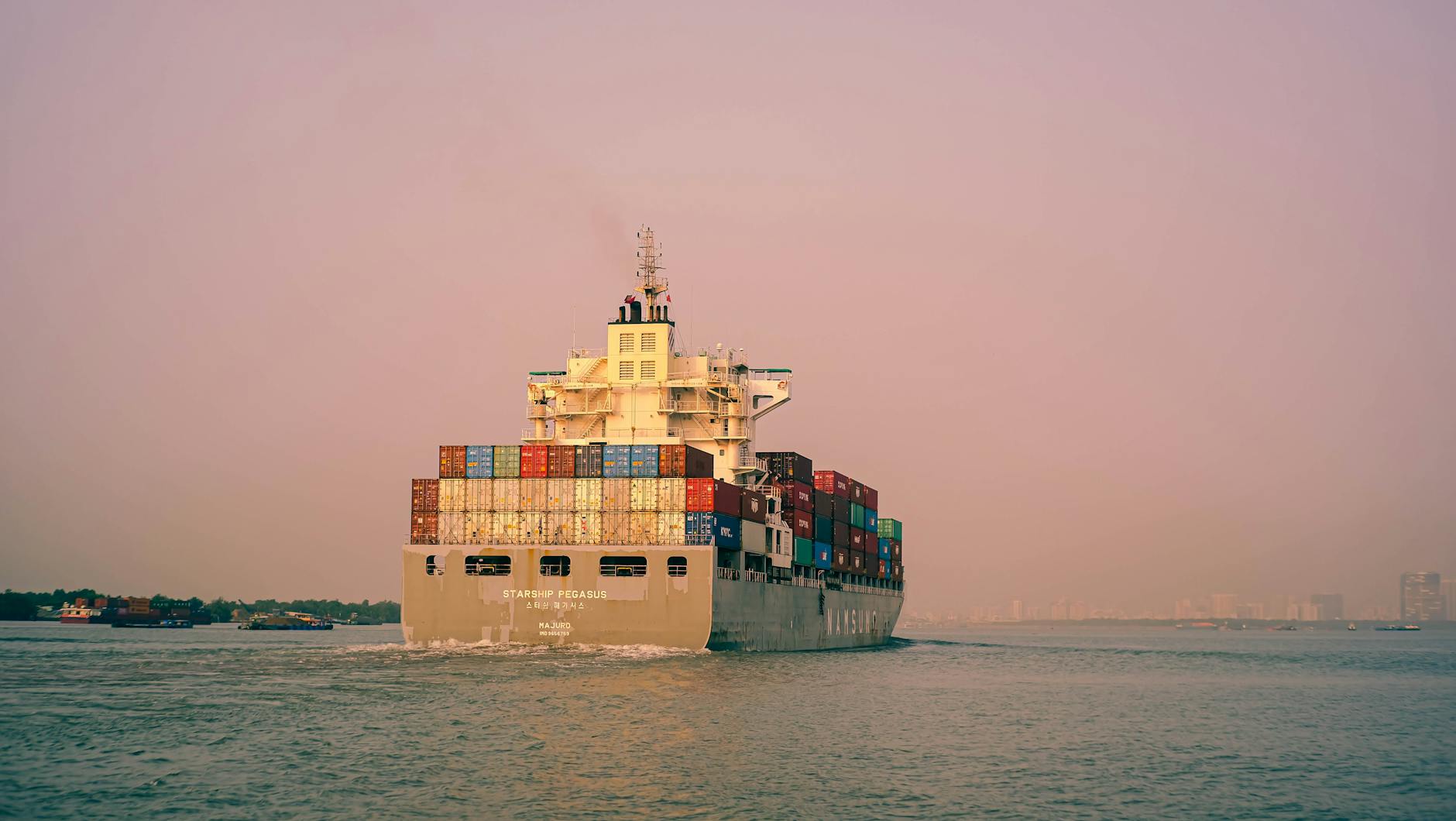 A large container ship sailing through tranquil waters near Đồng Nai, Vietnam, under a clear sky.