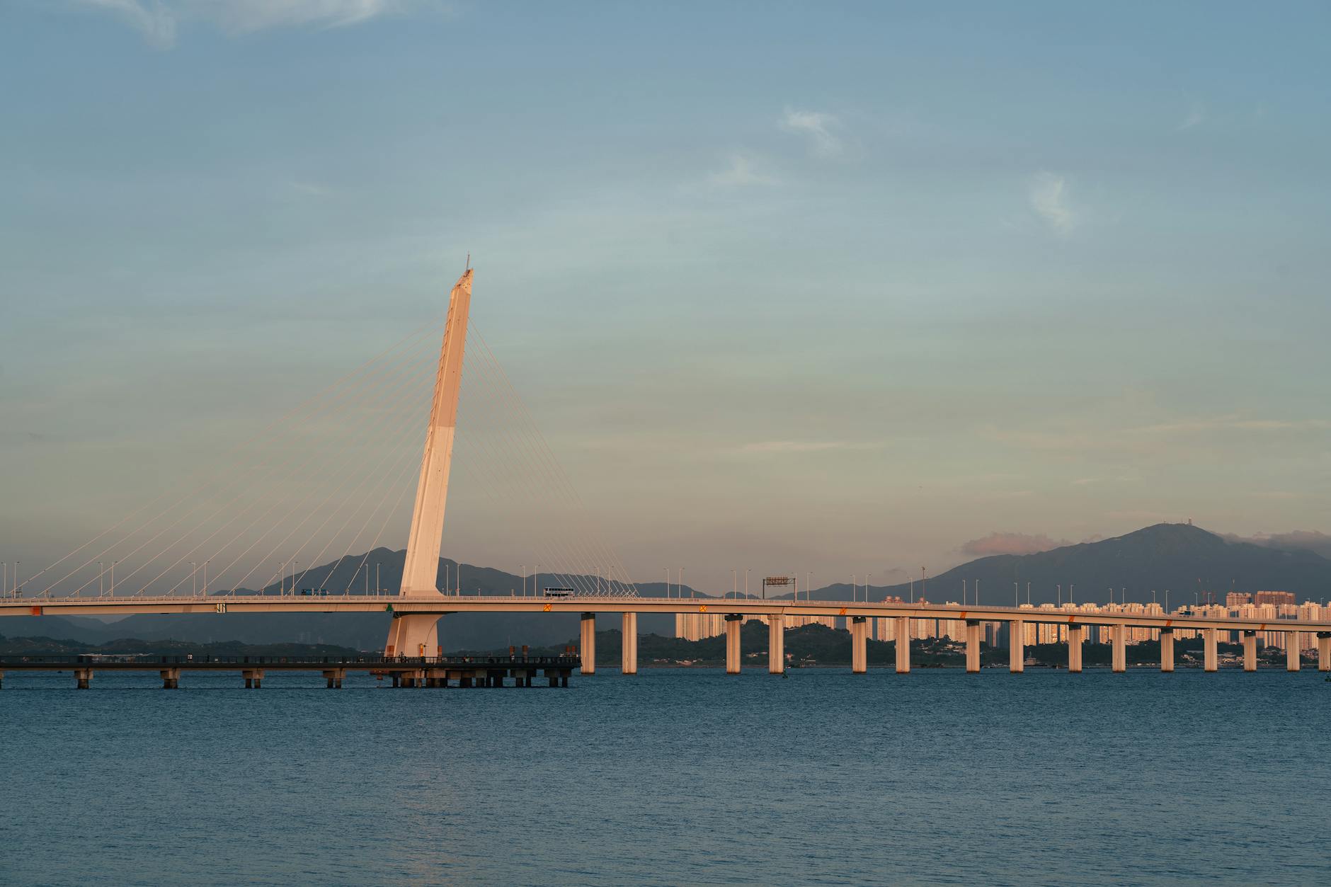 A scenic view of Shenzhen Bay Bridge at sunset, showcasing modern architecture and tranquil waters.