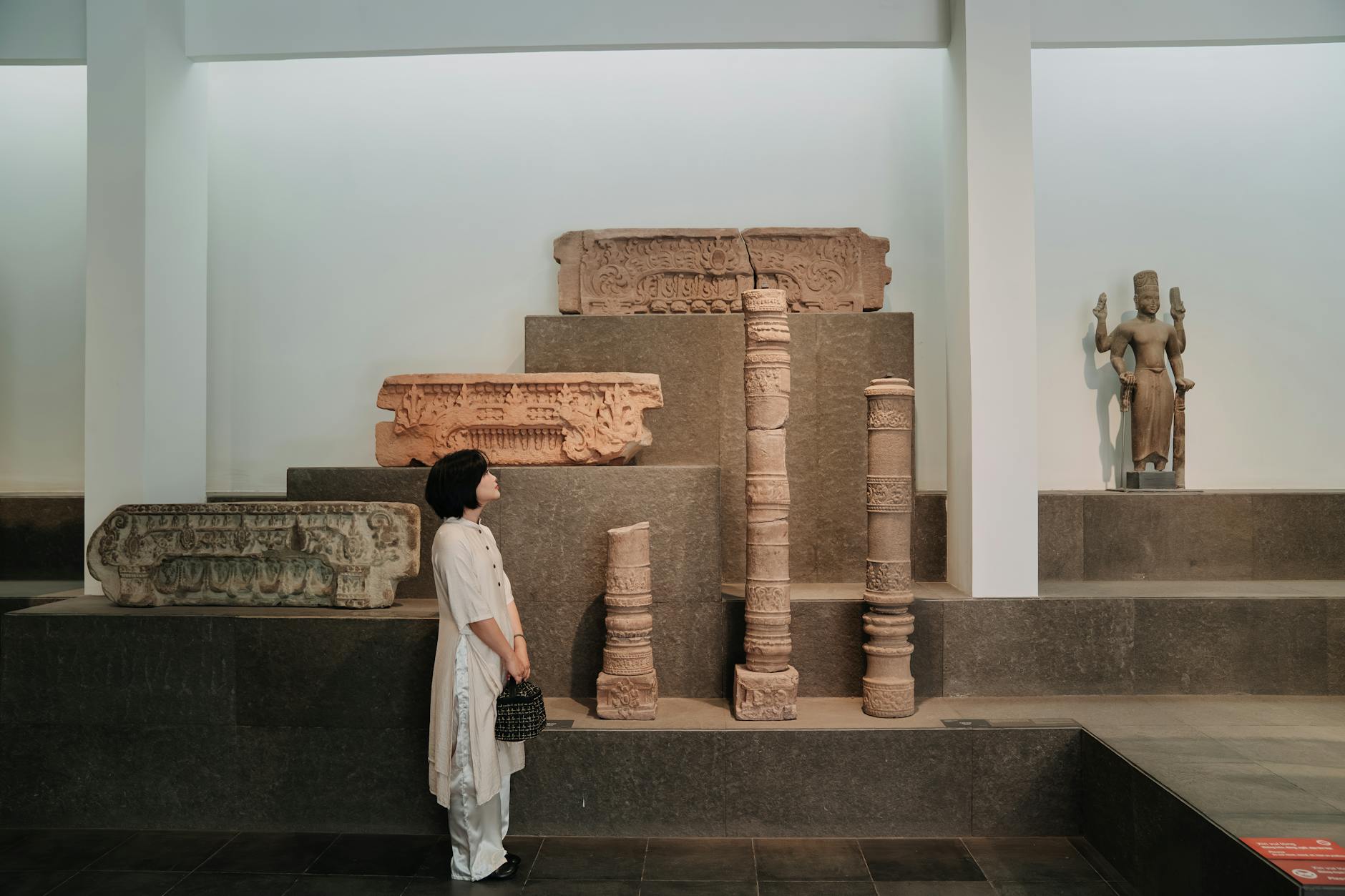 A woman observes historical artefacts in a well-lit museum exhibit.