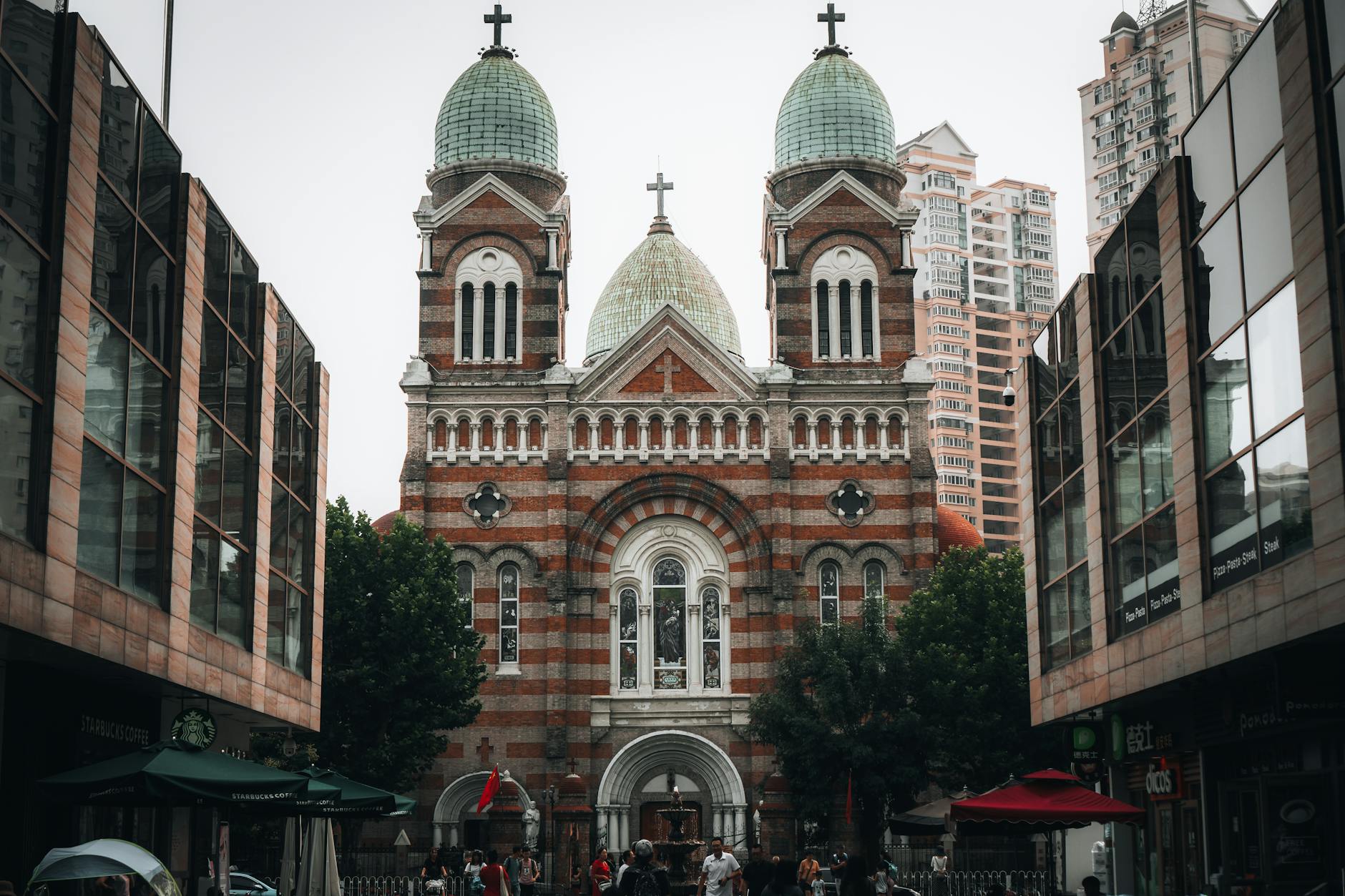 Saint Joseph Cathedral stands prominently against a backdrop of towering modern buildings, combining architectural styles.