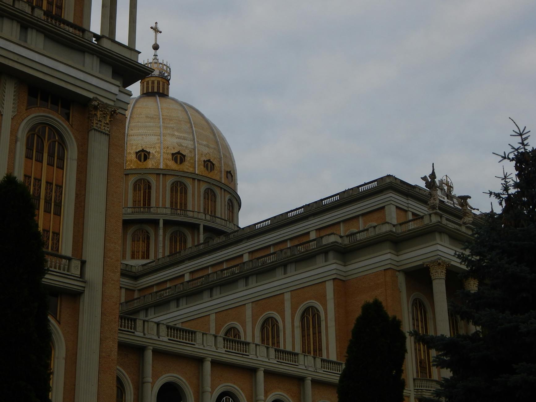 Golden dome of Licheń Basilica against a cloudy sky in Greater Poland.