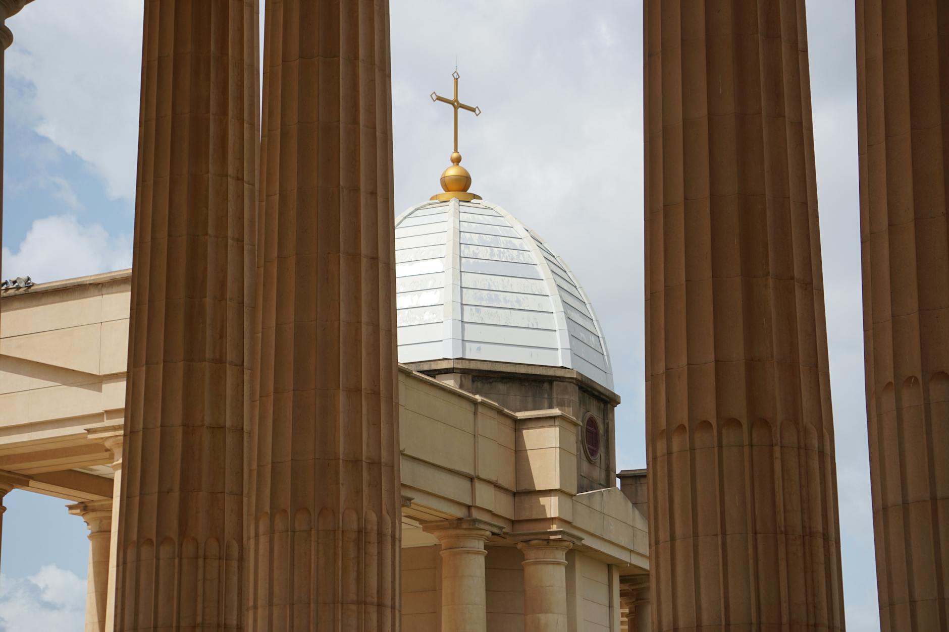 Low angle view of the Basilica of Our Lady of Peace dome framed by columns in Yamoussoukro, Côte d'Ivoire.