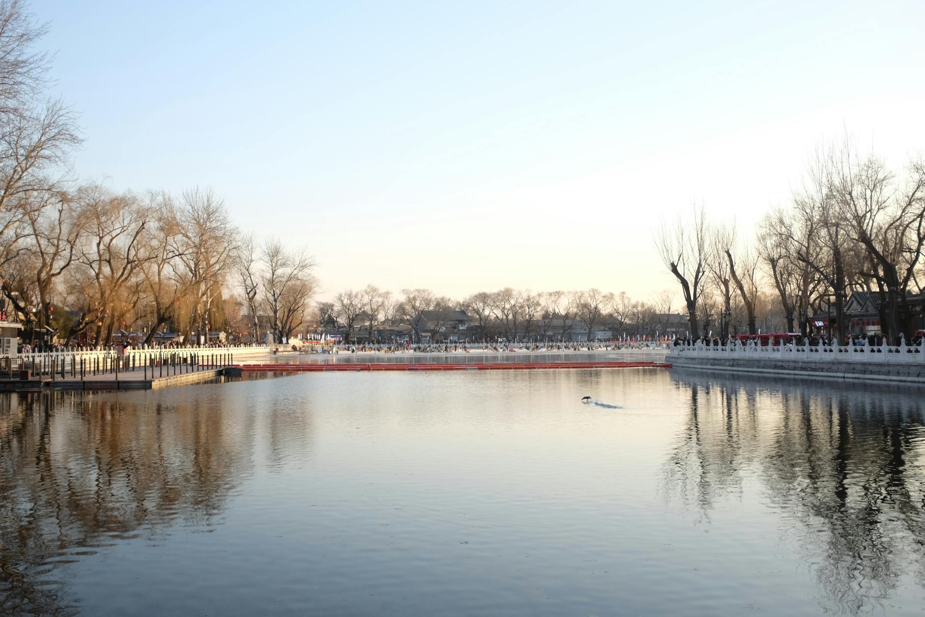 A tranquil winter view of Houhai Lake in Beijing, China, with reflections and bare trees.
