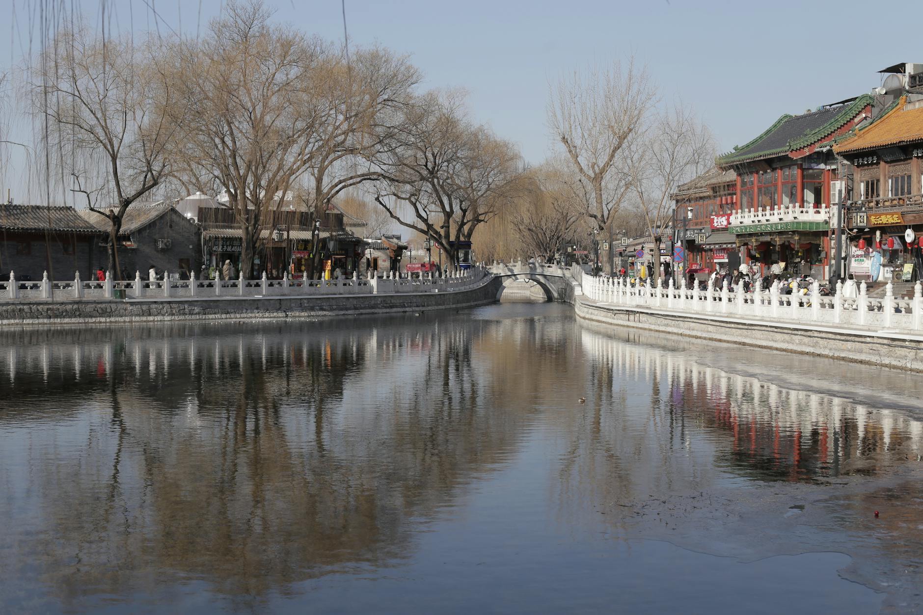 A serene view of a traditional Chinese canal and architecture in Beijing during winter.