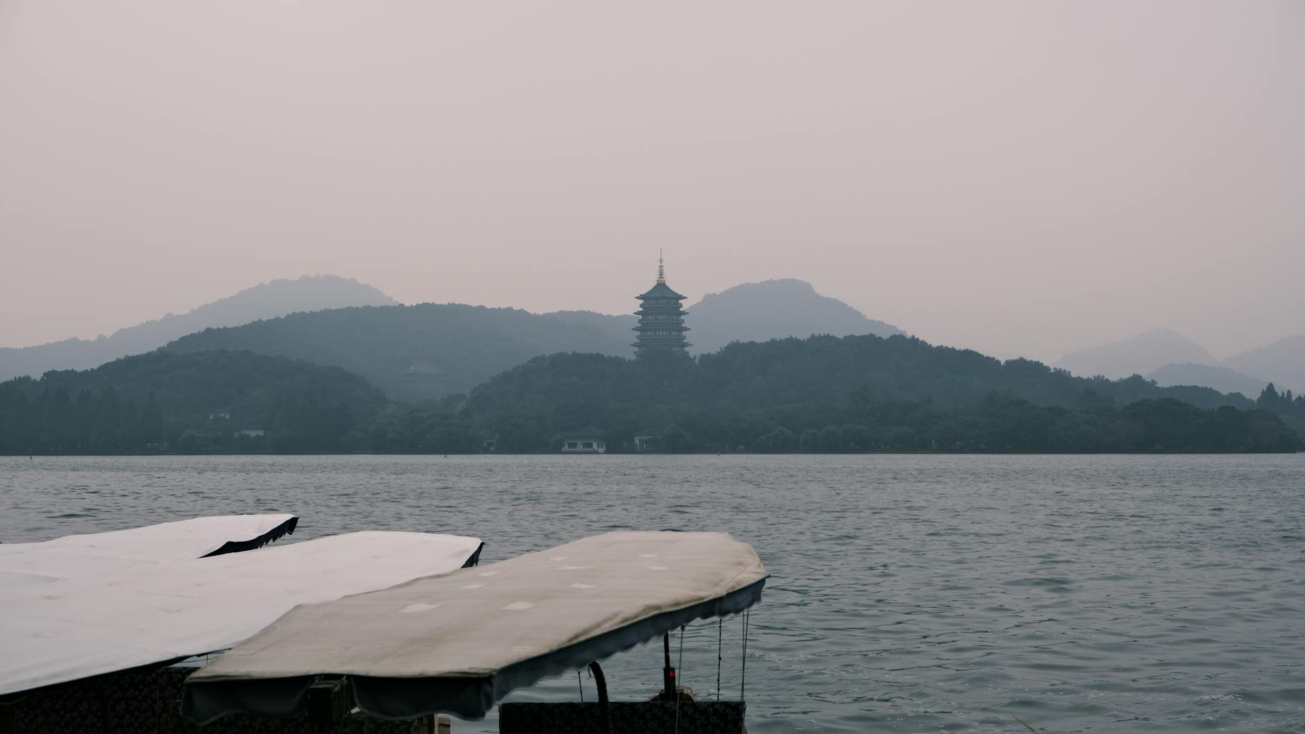 Calm West Lake waters with Leifeng Pagoda and misty mountains in Hangzhou, Zhejiang, China