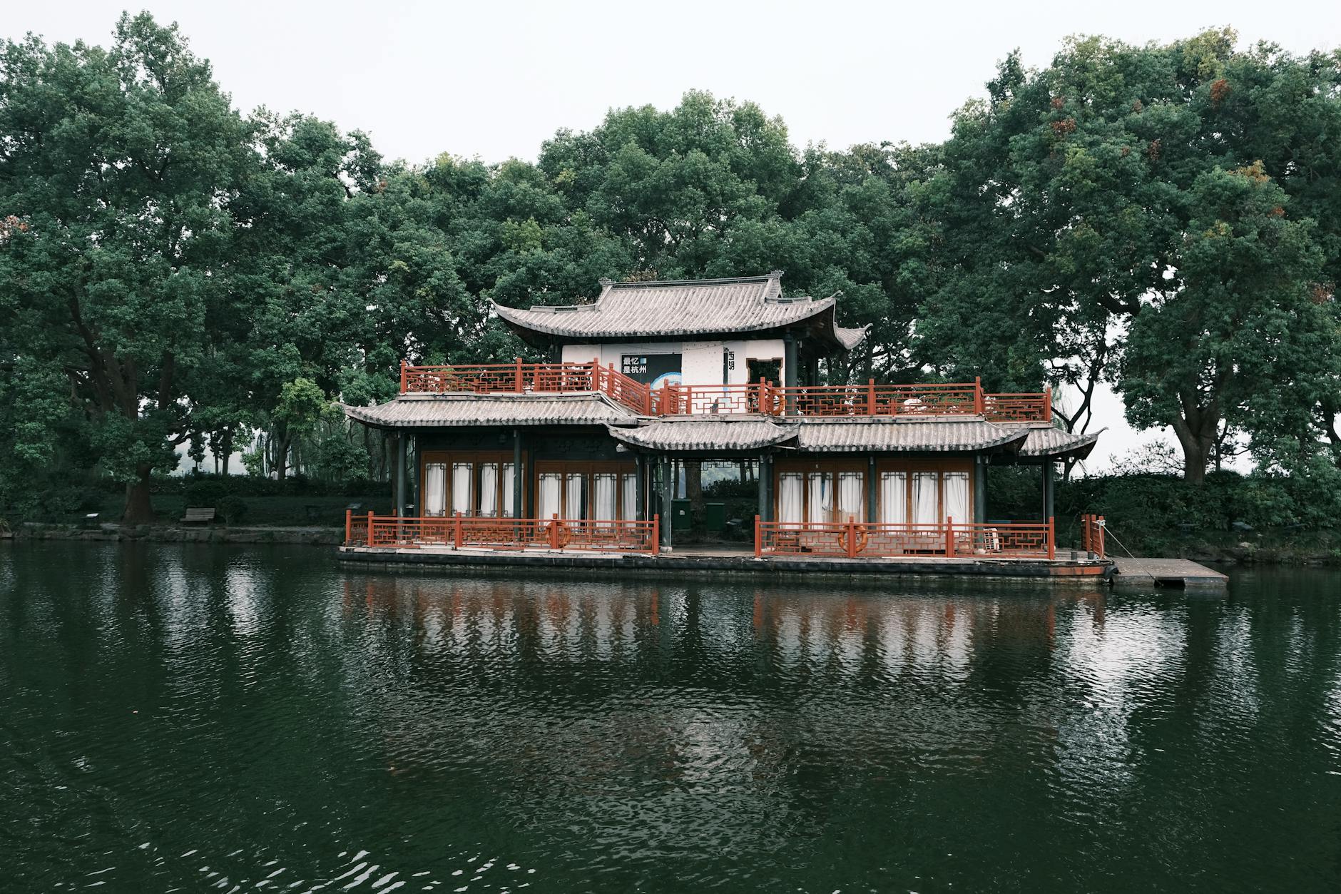Beautiful traditional Chinese building surrounded by lush trees and calm waters, reflecting cultural elegance.