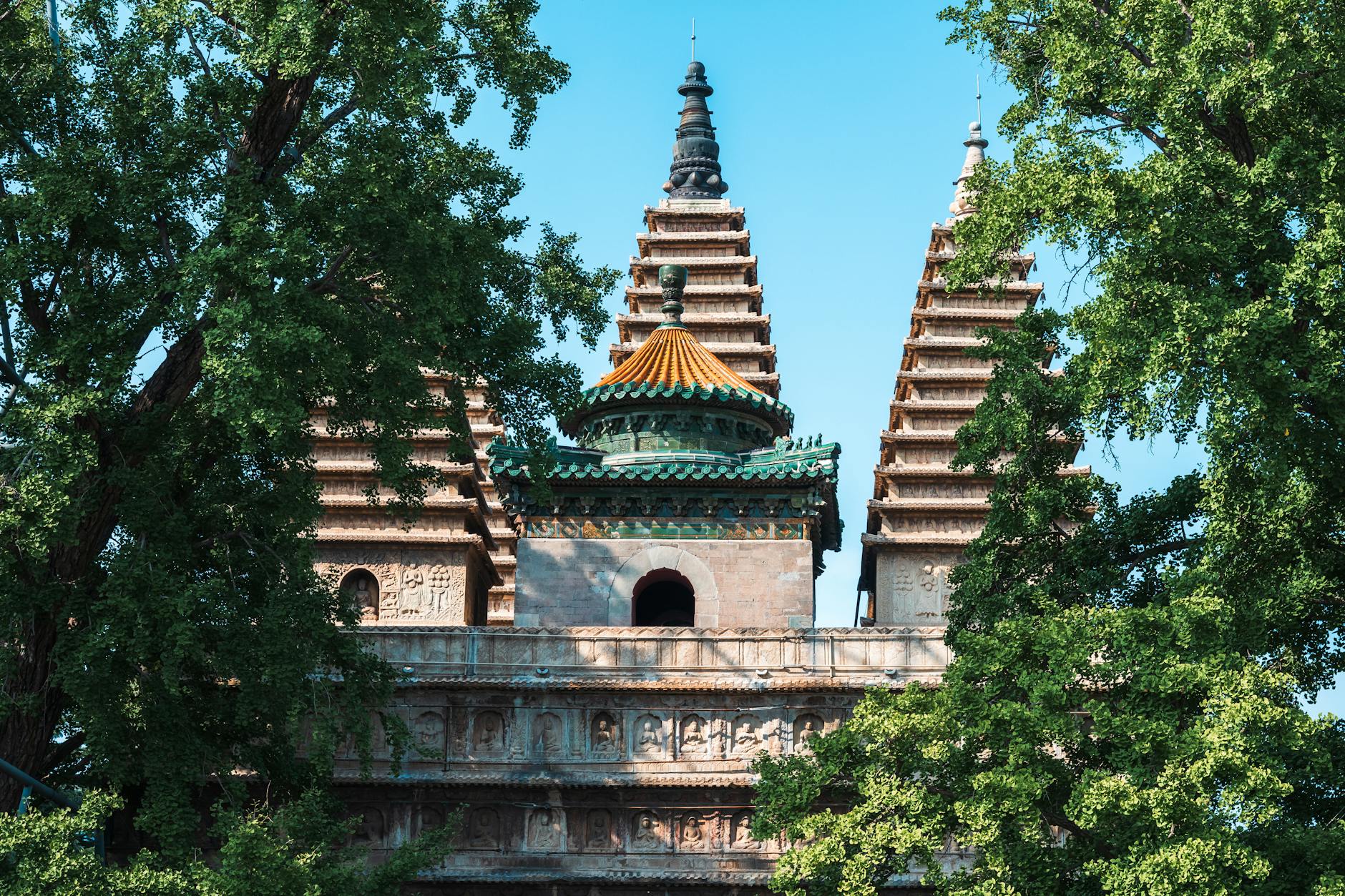 Historic Chinese pagoda surrounded by lush green trees under a clear blue sky.