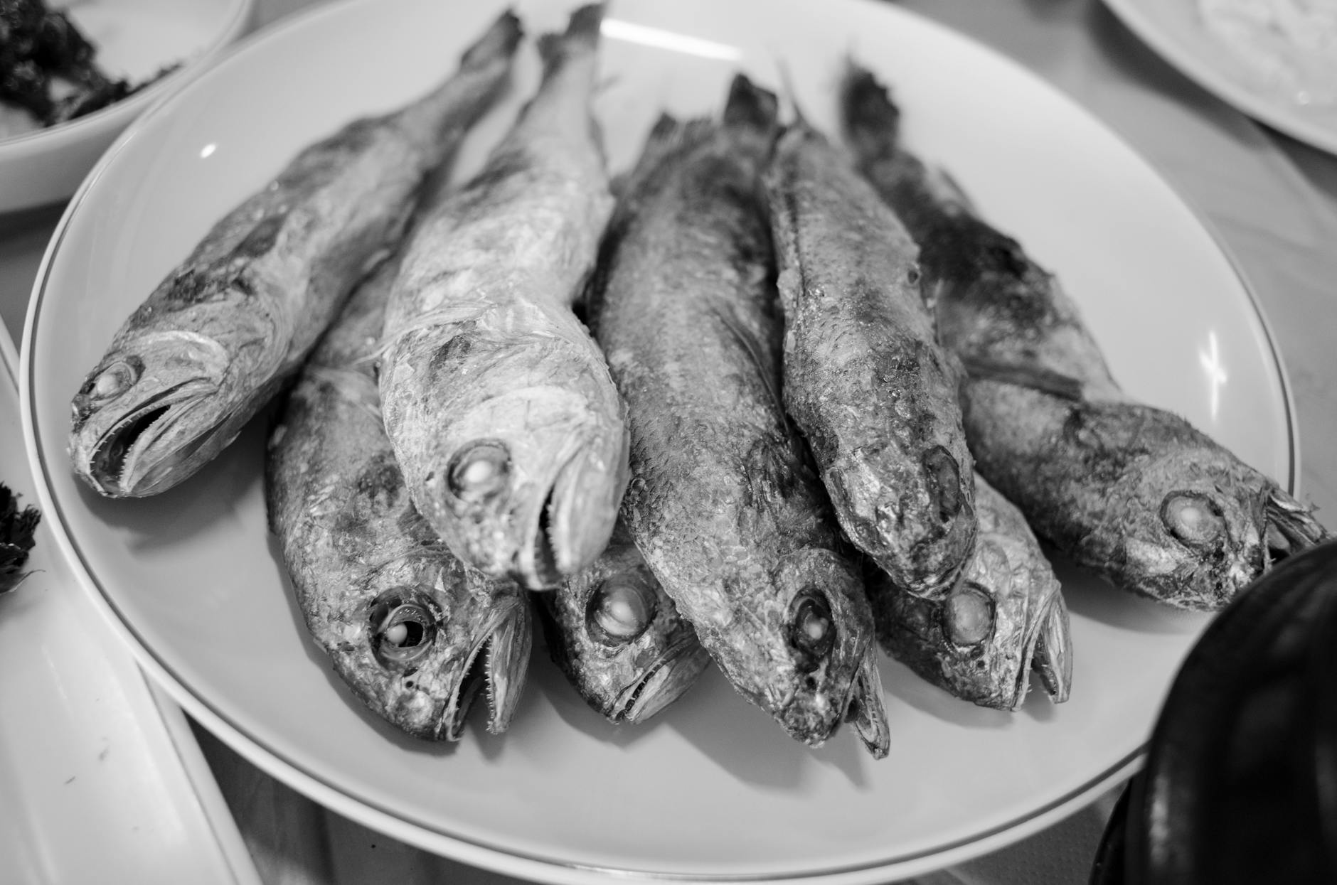 Close-up of a dish with fried fish in a black and white setting. Perfect for culinary or seafood themes.
