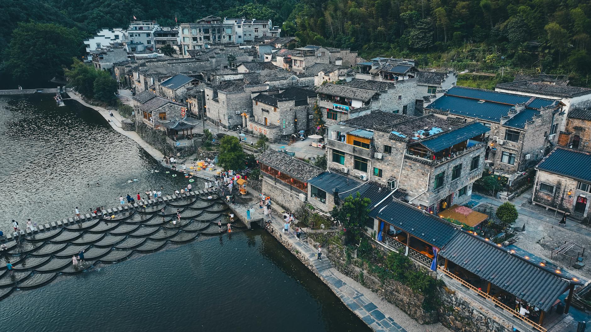 A beautiful aerial view of an ancient Chinese town nestled beside a flowing river, showcasing its historic architecture.