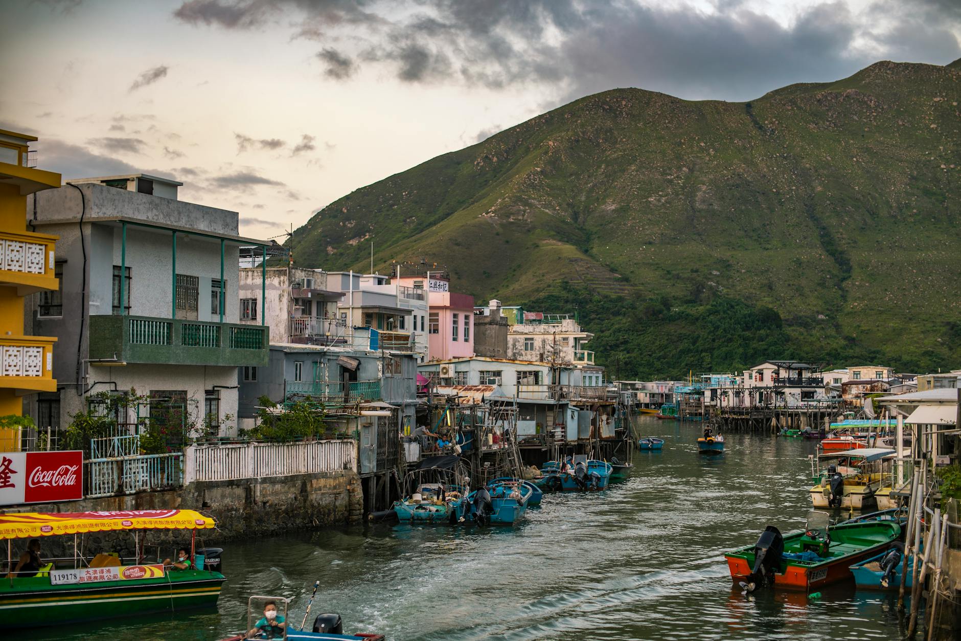 Charming view of Tai O fishing village with boats and stilt houses against a mountain backdrop.