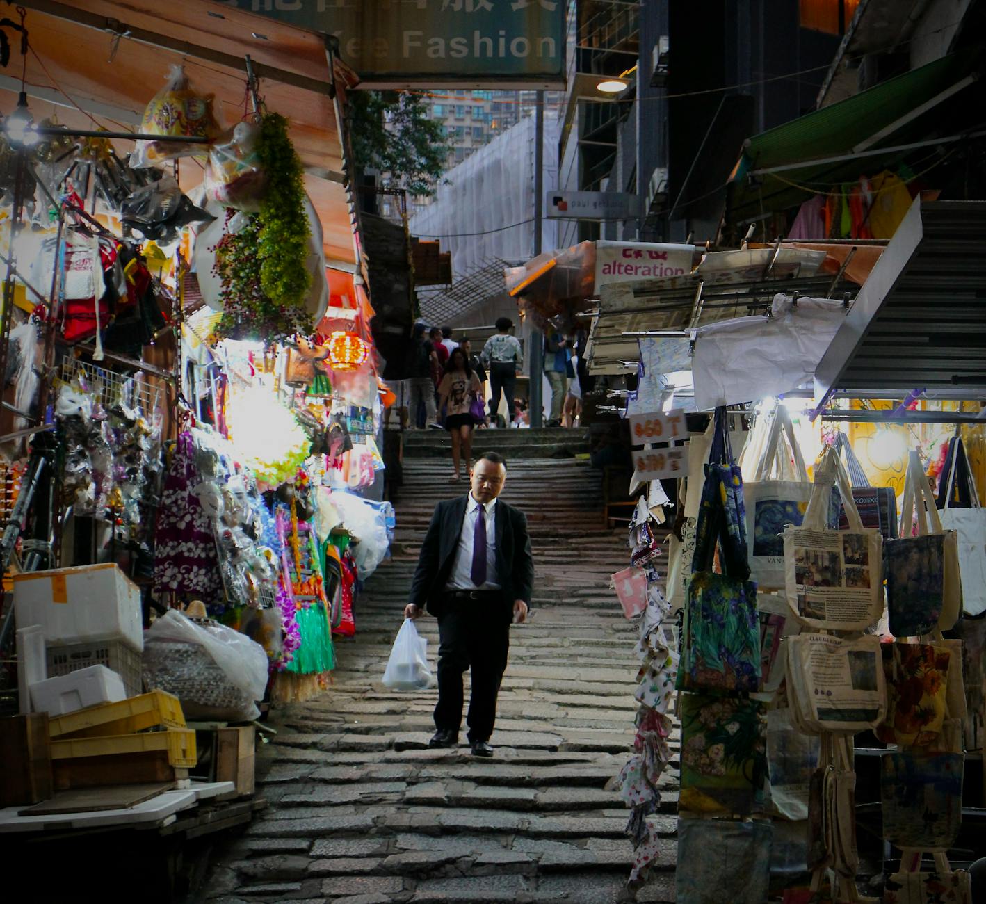 Businessman walking through a colorful market on Hong Kong Island, showcasing local culture and vibrant stalls.