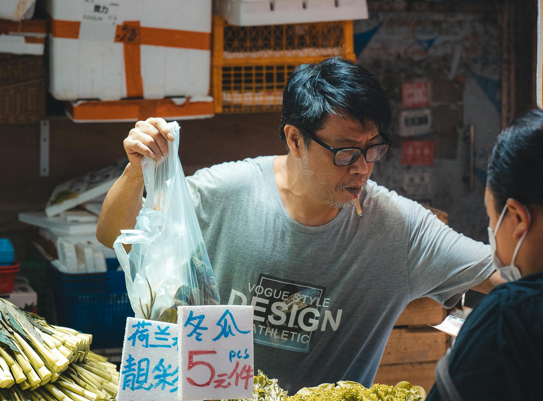 A vendor in a Hong Kong street market selling fresh vegetables to customers.