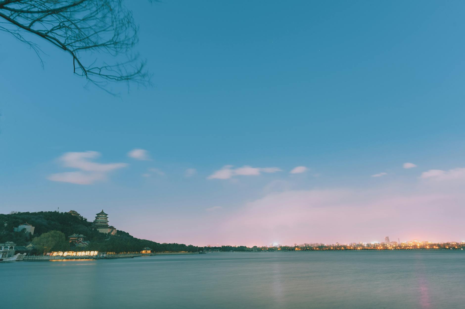 Beautiful view of the Summer Palace at sunset with a serene lake and city skyline in Beijing, China.