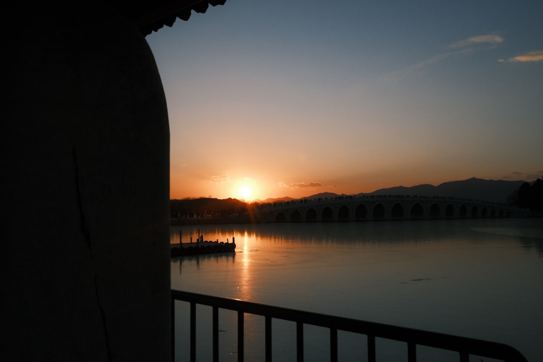 Sunrise over a tranquil lake with a bridge.