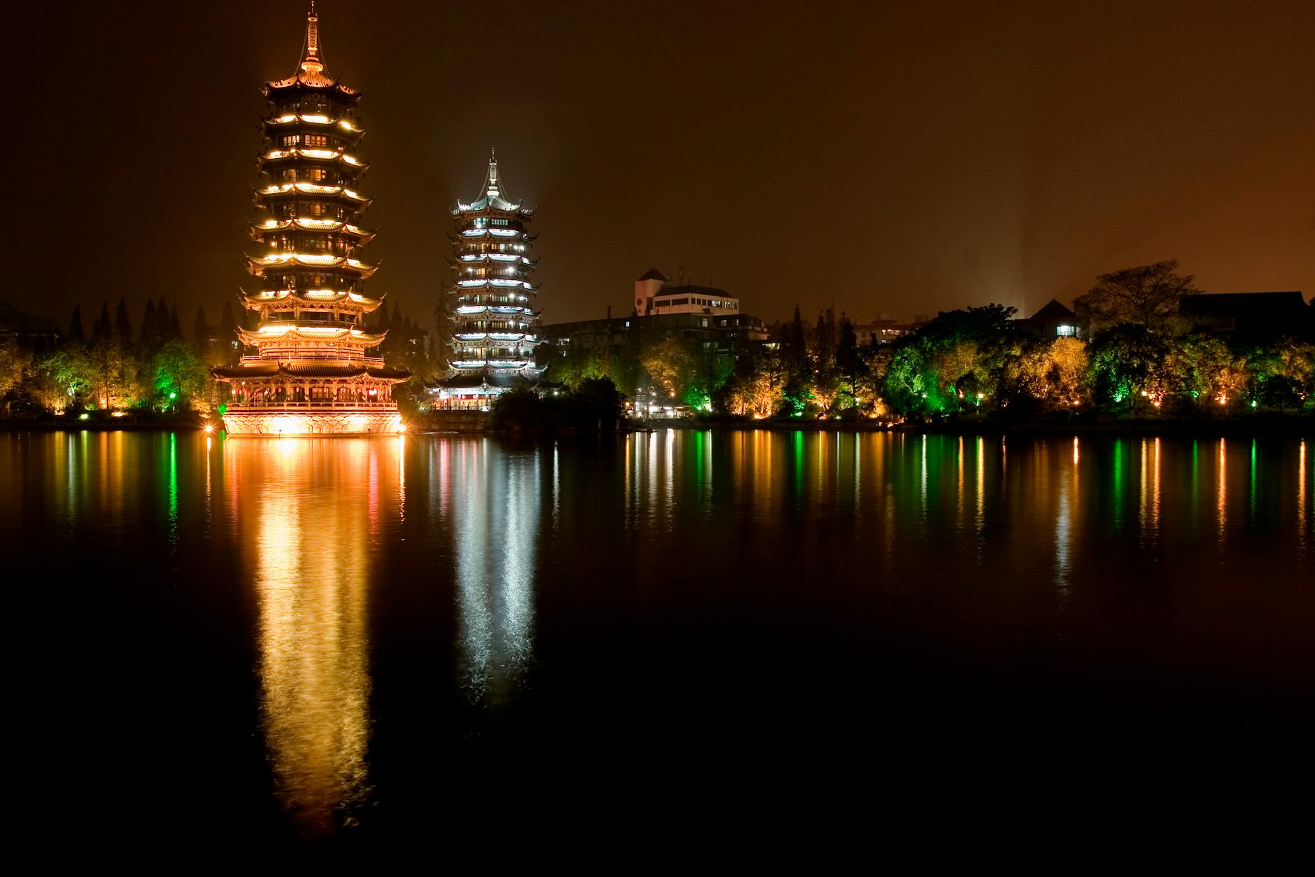 Stunning nighttime view of the Sun and Moon Pagodas in Guilin, reflecting on the water.