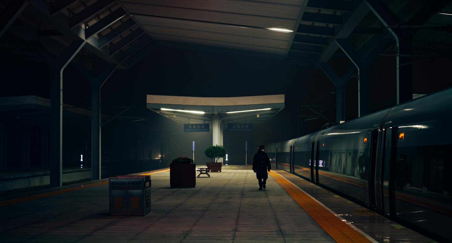 A silhouette of a man at a quiet train station at night, conveying solitude and travel.