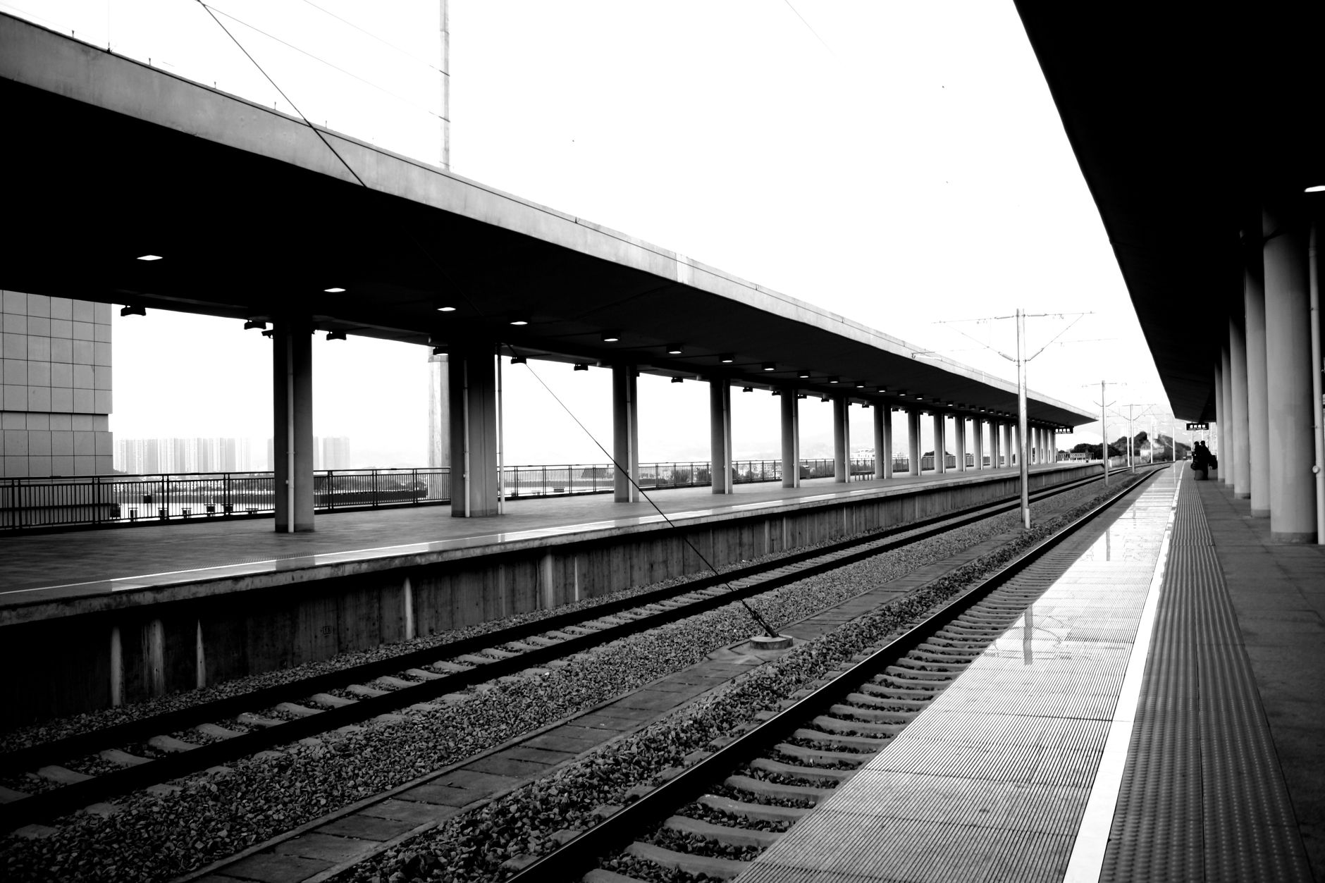 Desolate railway platform in black and white showcasing urban architecture and symmetry.