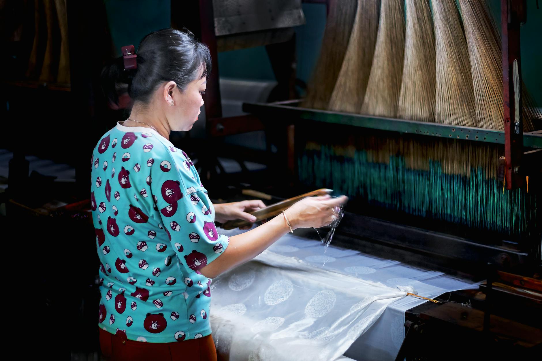 A woman weaving silk in a traditional workshop in Tân Châu, Vietnam, showcasing local craftsmanship.