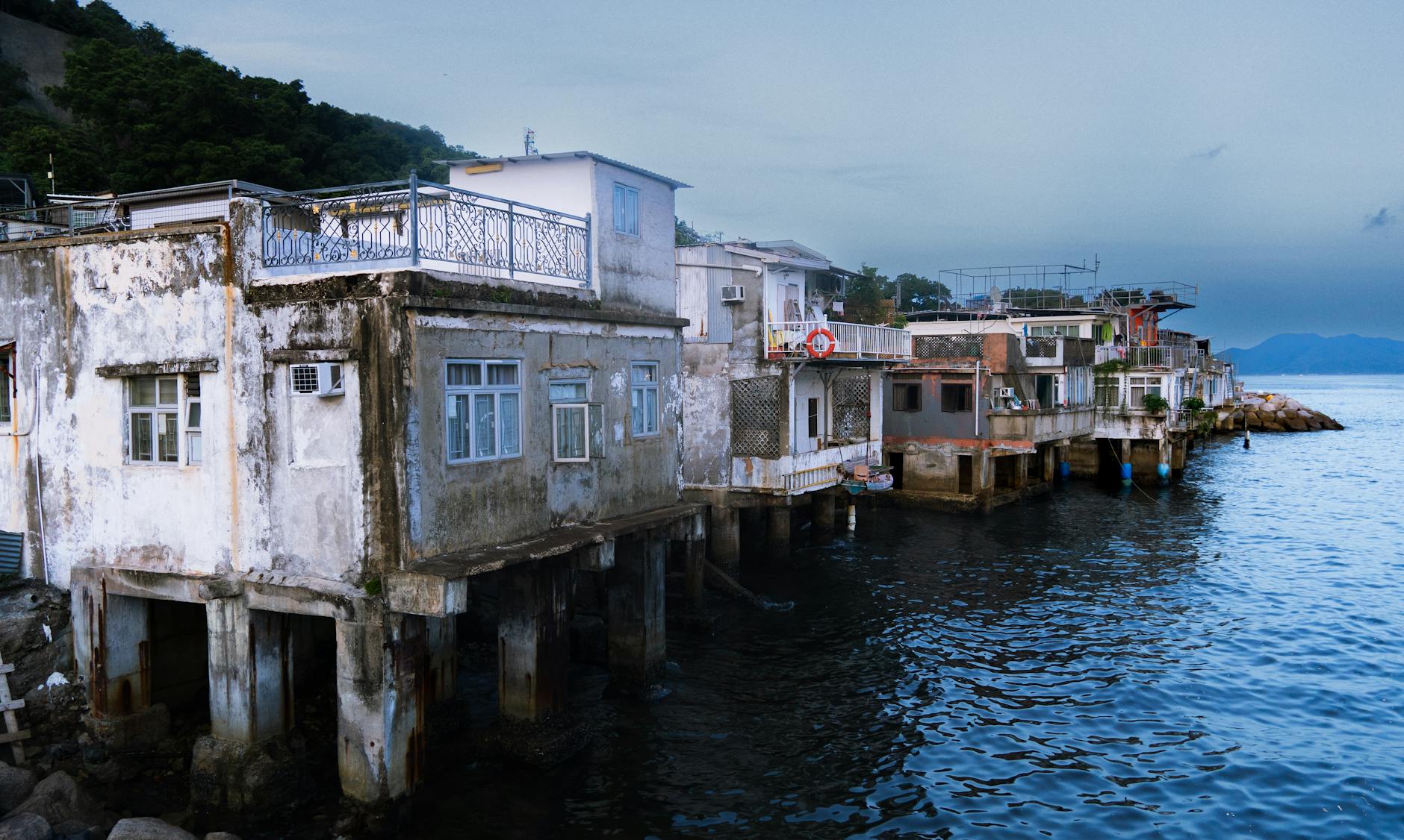 Rustic seaside houses on stilts near a tranquil shoreline under twilight.