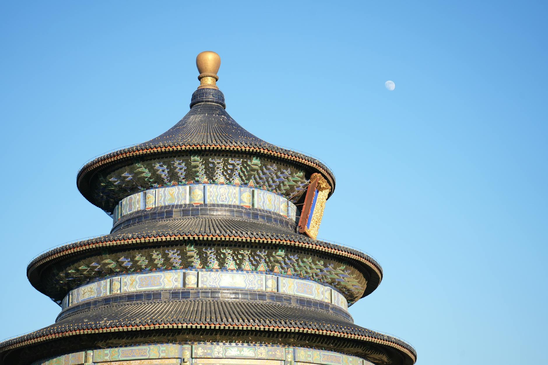 Iconic Temple of Heaven with a clear blue sky and moon in Beijing, China.
