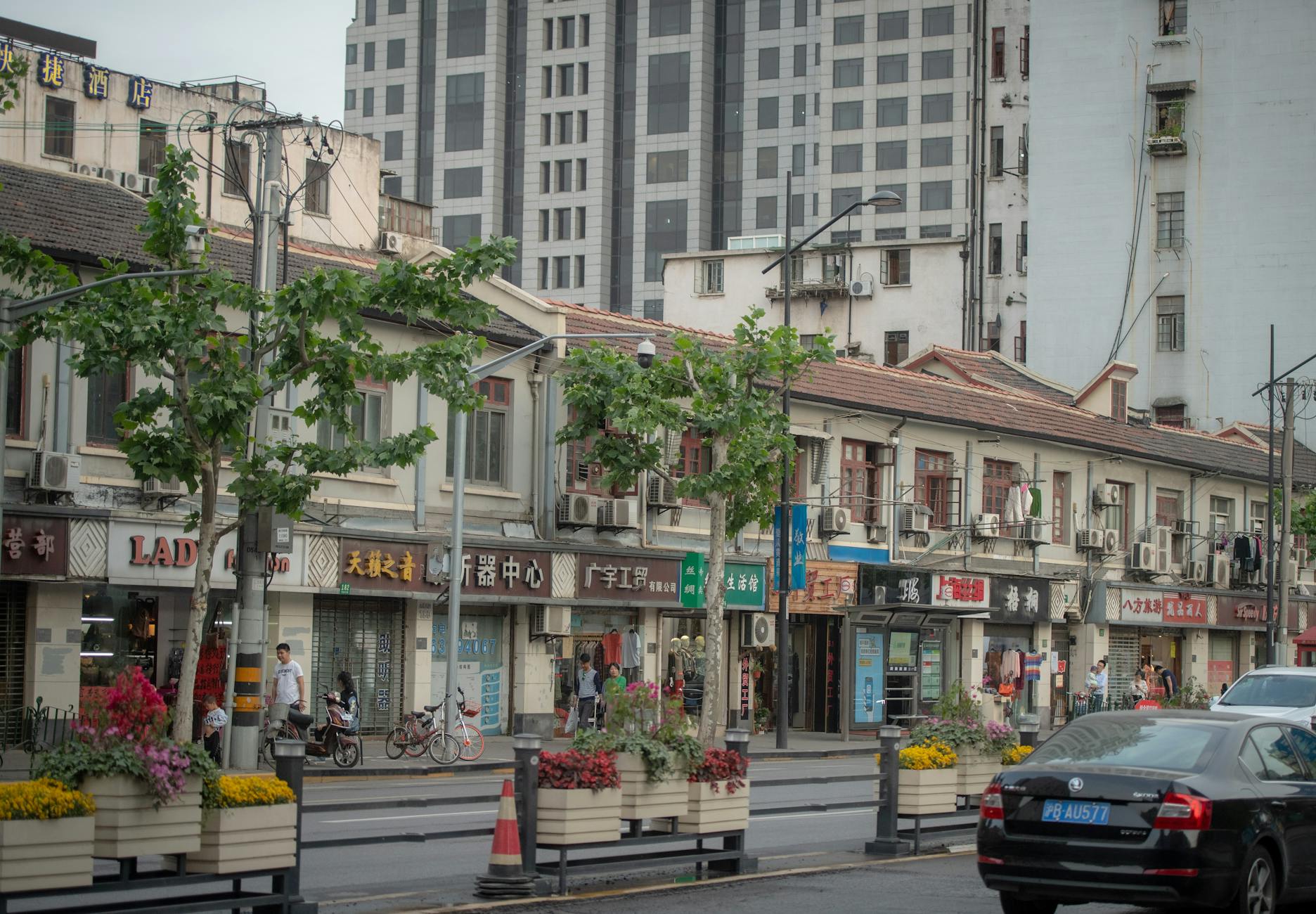 Charming Shanghai street with small businesses and modern architecture in the background.