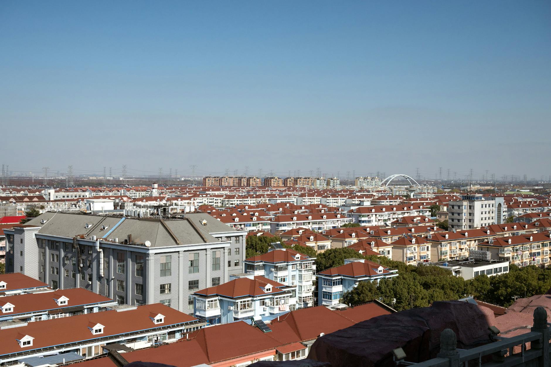 A scenic aerial view of Shanghai's red-roofed residential district under a clear blue sky.
