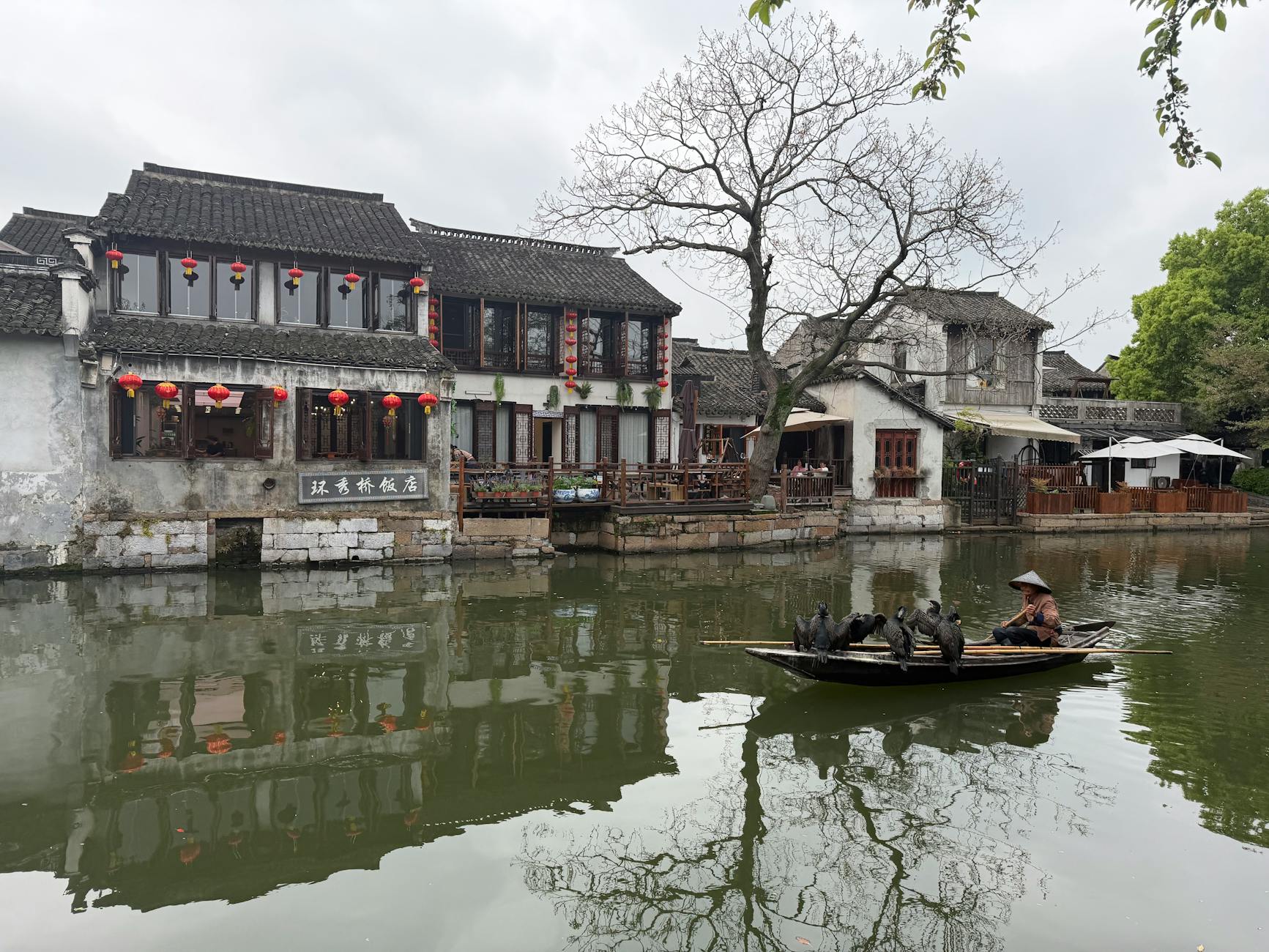 Fisherman in a boat at a tranquil water town, showcasing traditional buildings.