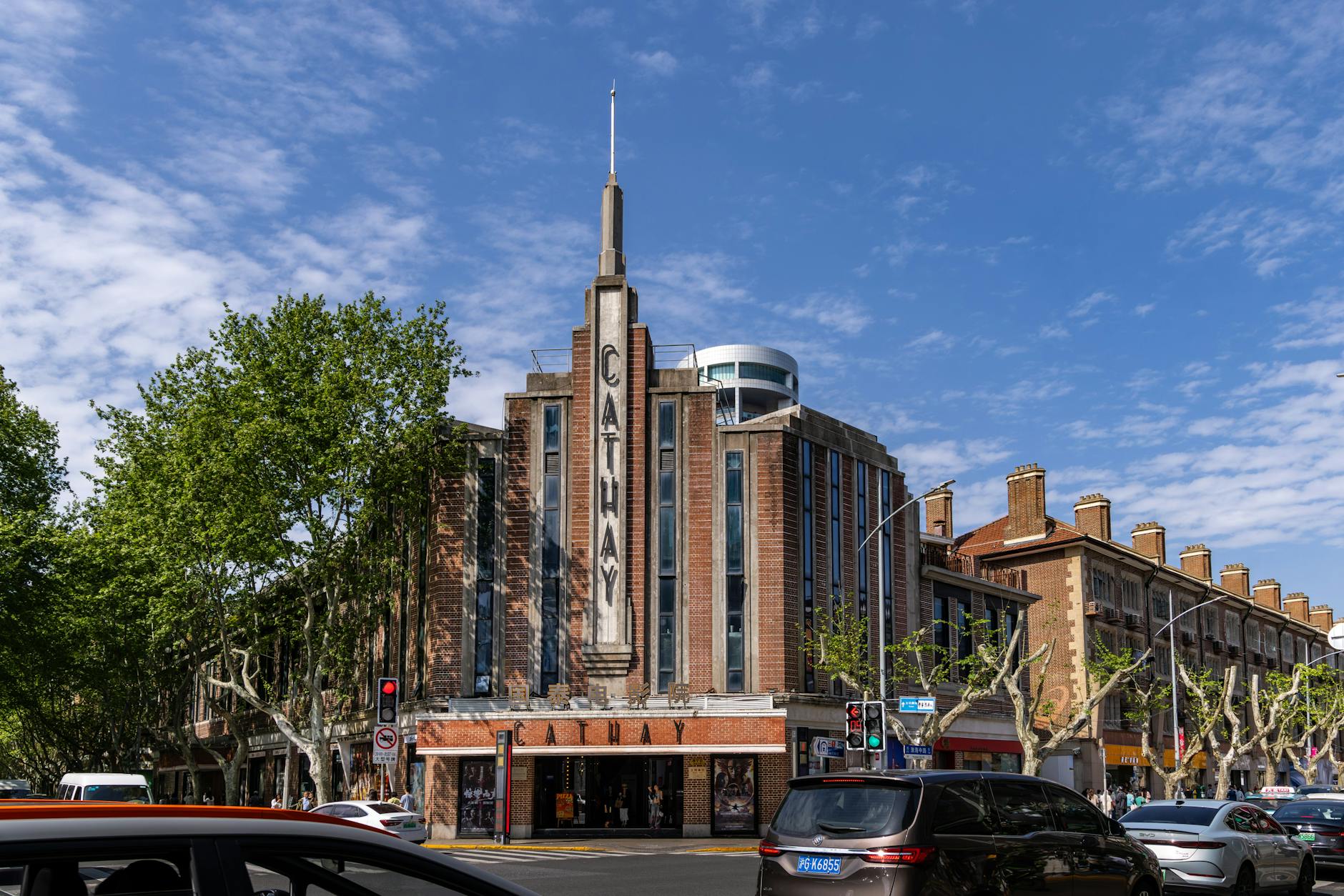 Classic Art Deco architecture of Cathay Cinema in Shanghai with vibrant urban surroundings on a sunny day.
