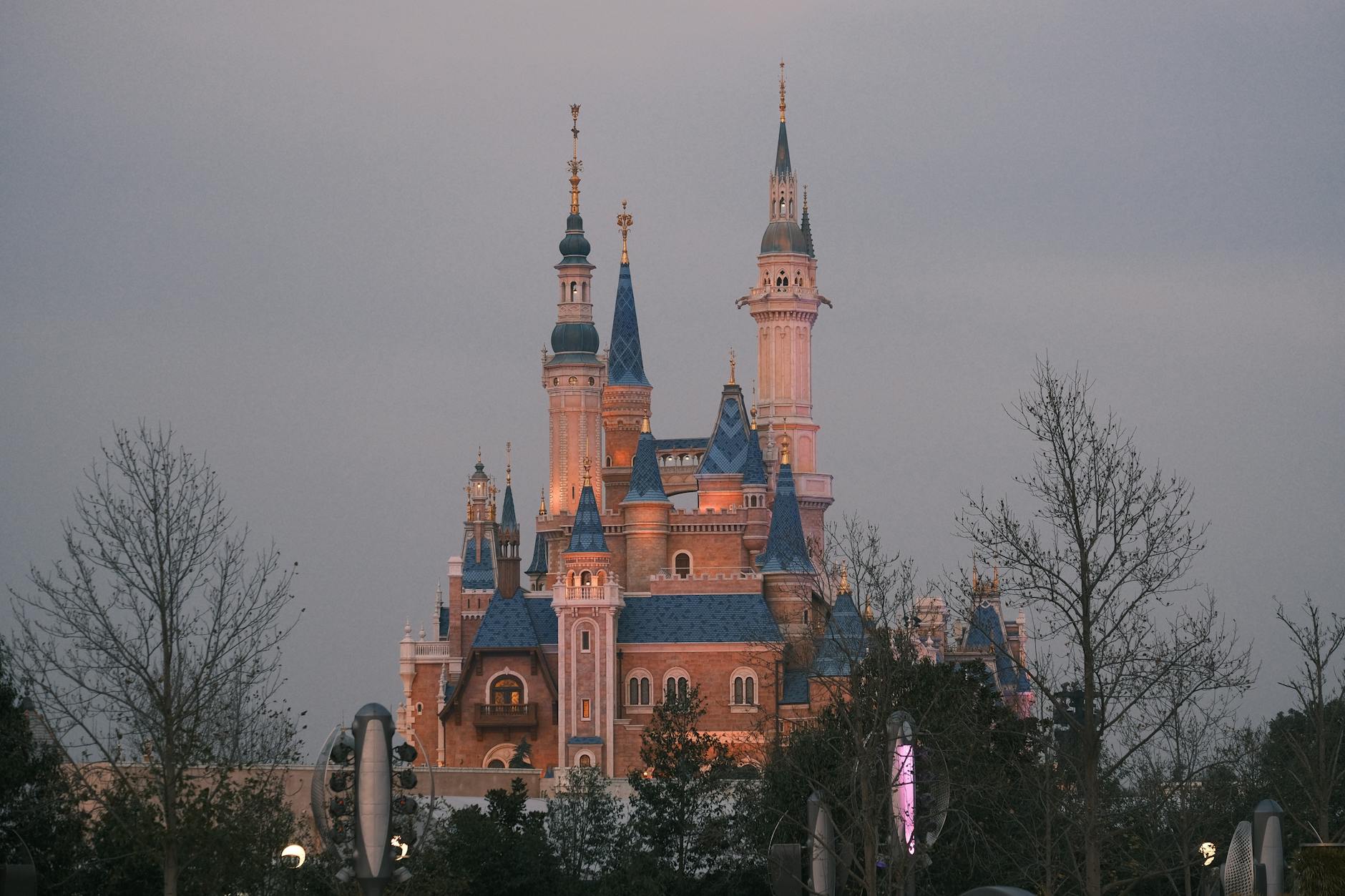 Twilight view of the enchanting castle at Shanghai Disney Resort, surrounded by trees.