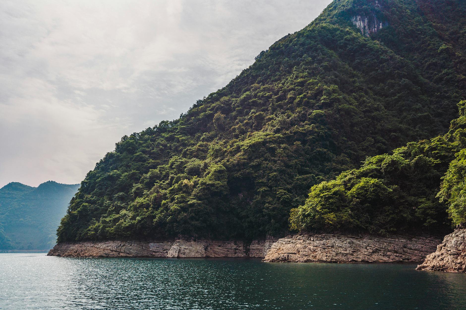 Spectacular view of lush green mountains meeting the tranquil waters of Yichang's coast in Hubei, China.