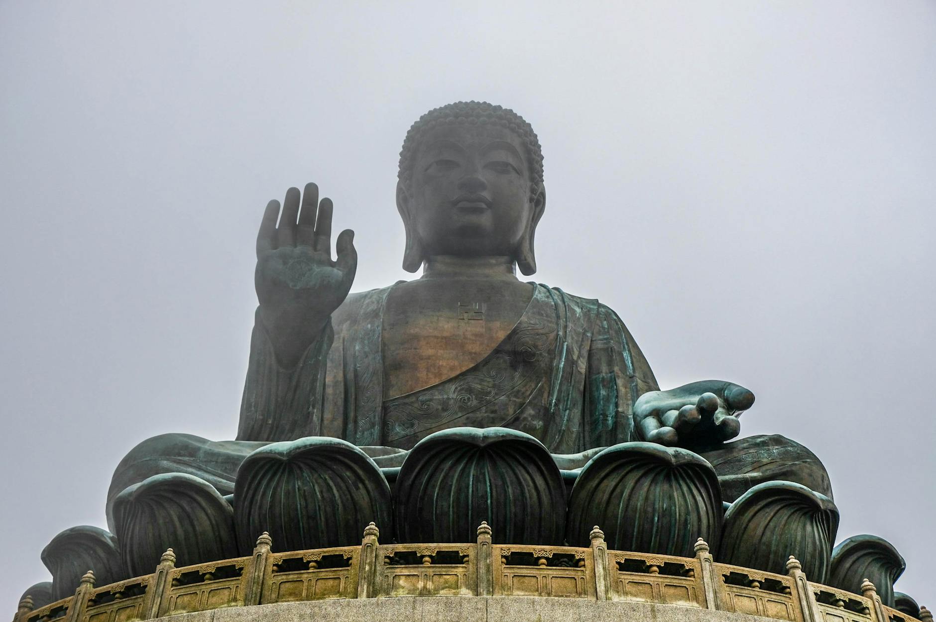 Majestic Tian Tan Buddha statue on Lantau Island, Hong Kong in misty weather seen from below.