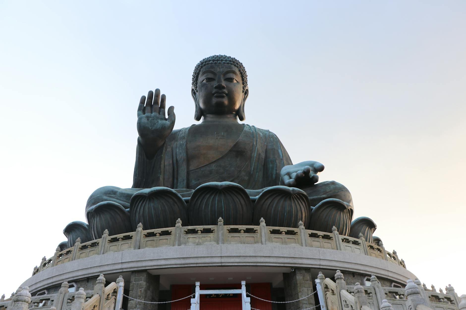 Low angle view of the iconic Tian Tan Buddha statue under a clear sky in Hong Kong.