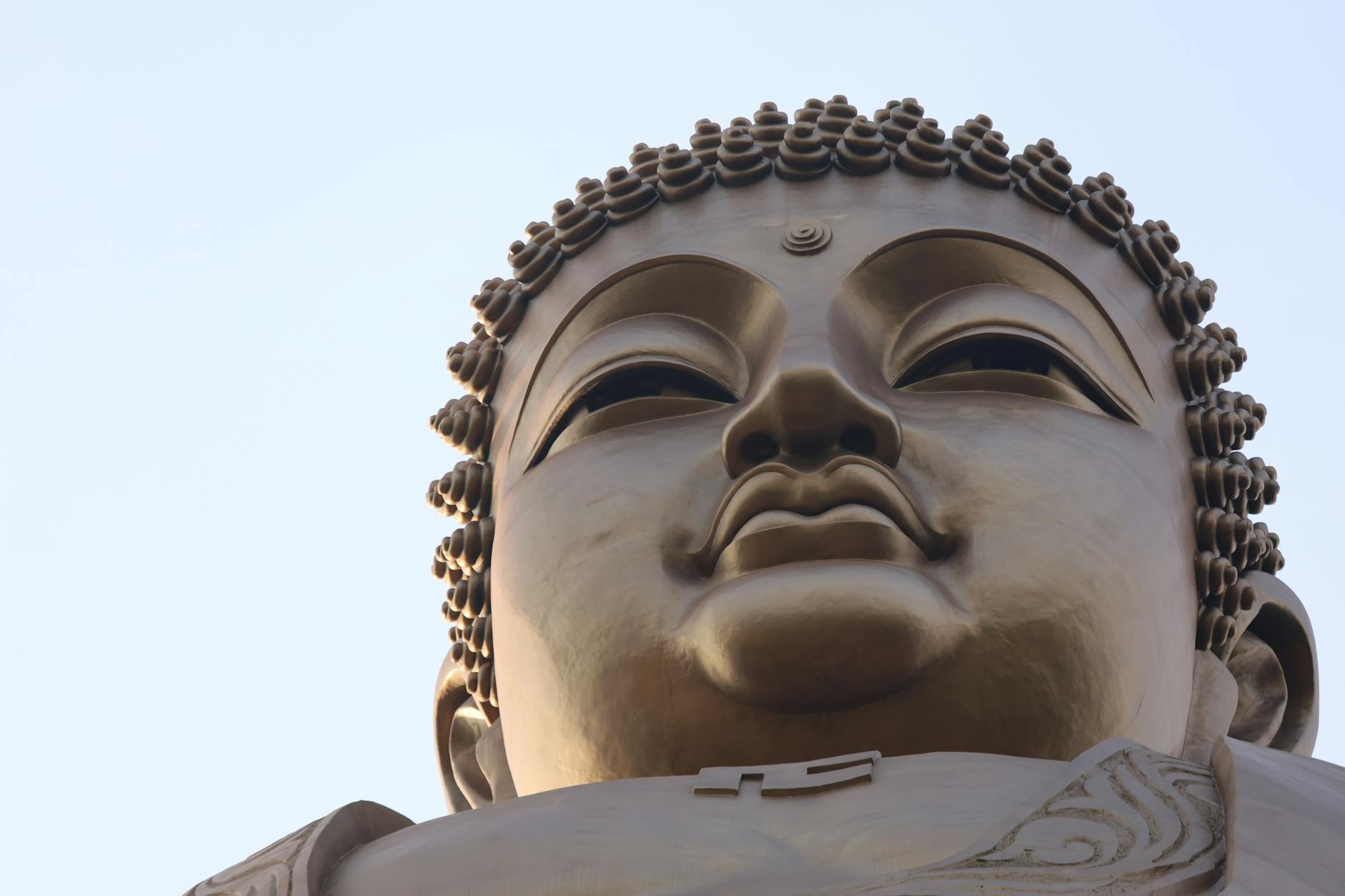 Detailed close-up of the bronze Tian Tan Buddha statue against a serene sky.