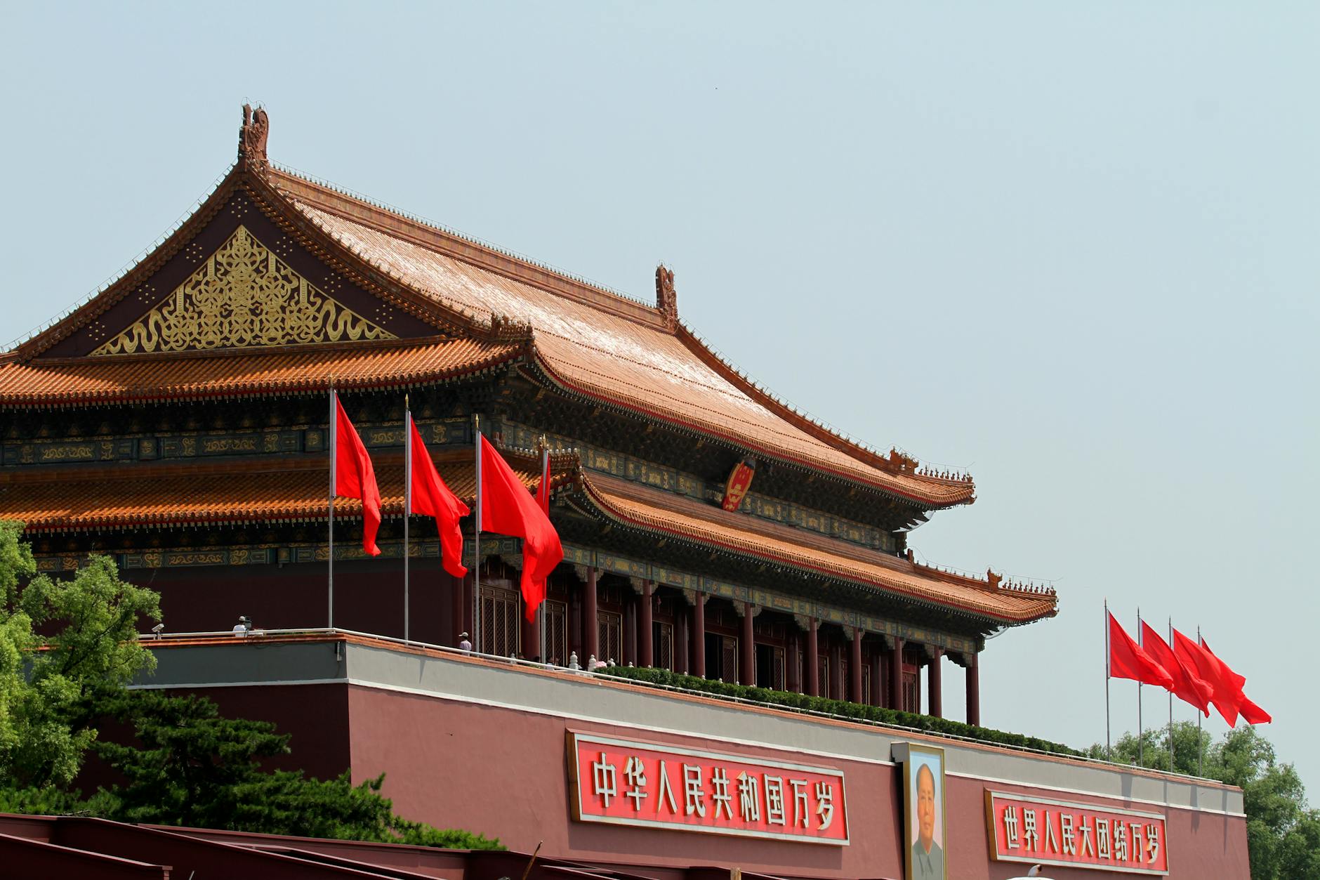 Tiananmen Gate in Beijing, China with vibrant red flags under a clear sky.