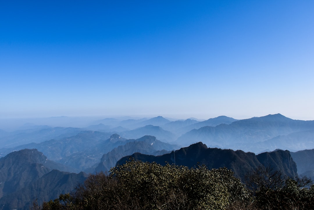 thin fogs covering the green mountain under clear blue sky