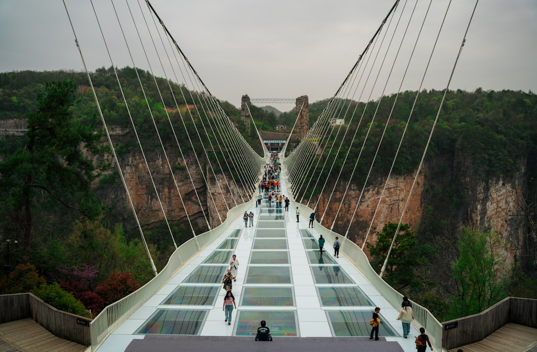 People walk across a glass bridge.