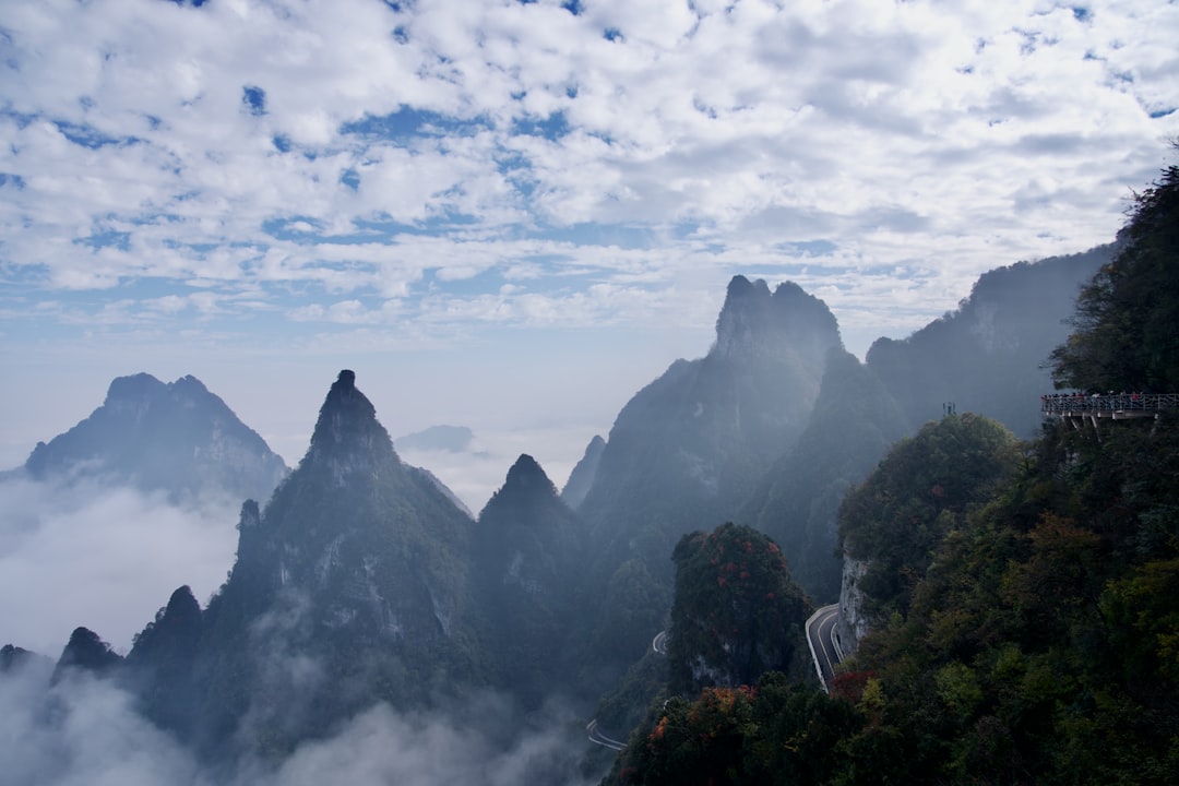 Misty mountains with a winding road and clouds.