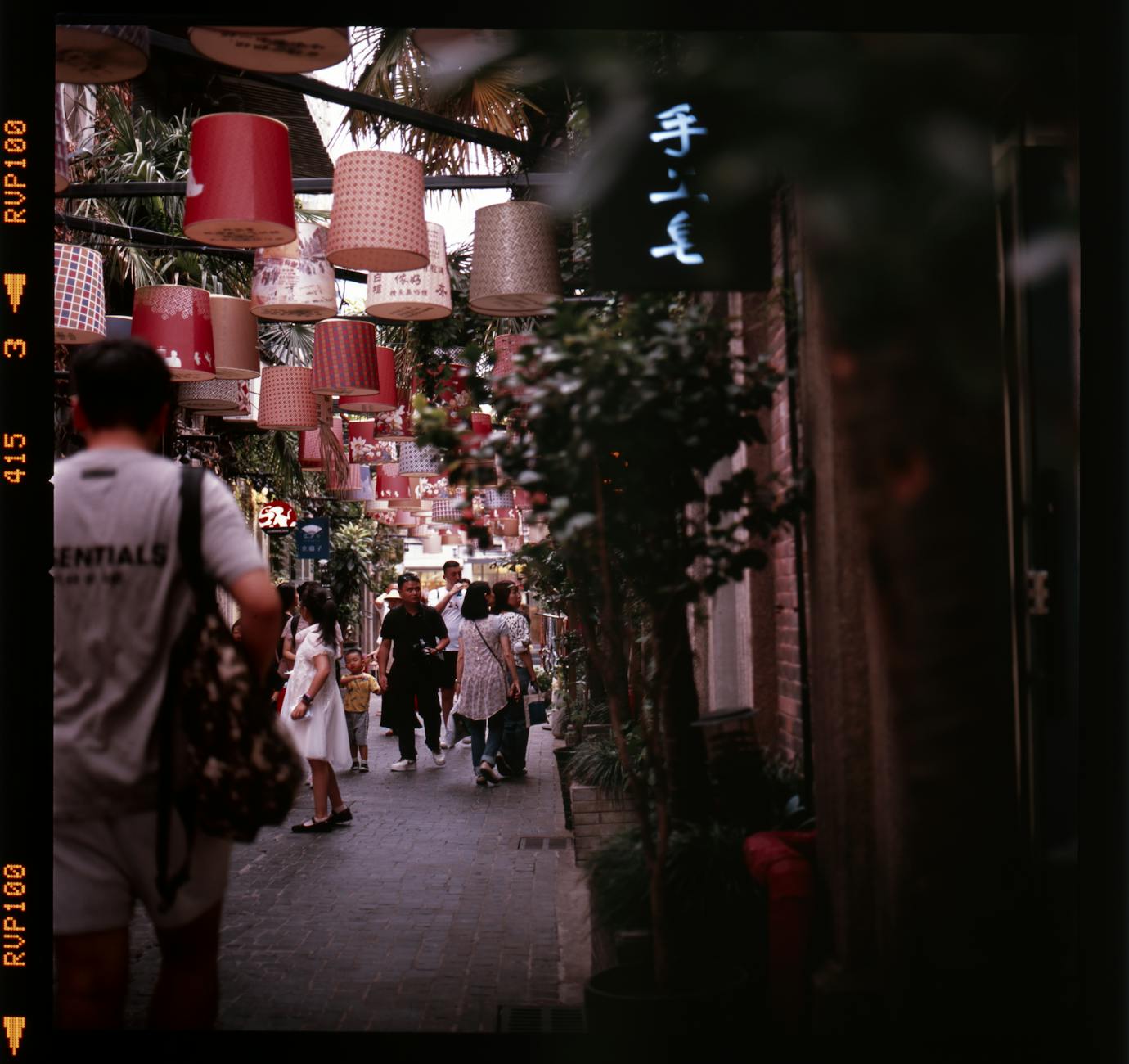 Colorful lanterns decorate a lively street in Tianzifang, Shanghai, vibrant with people.